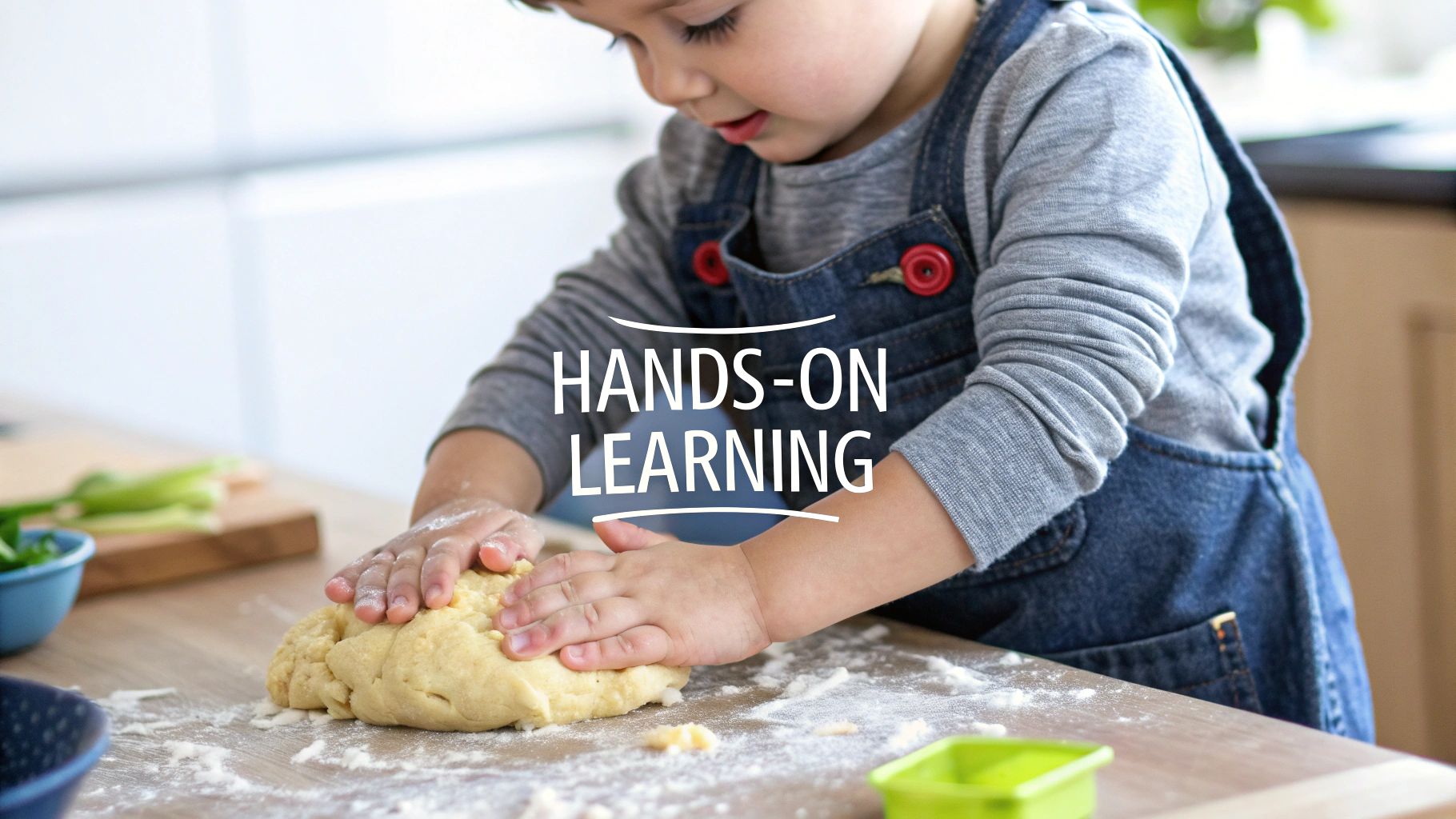 A child stands in in a Montessori learning tower, looking engaged while helping with a kitchen task.