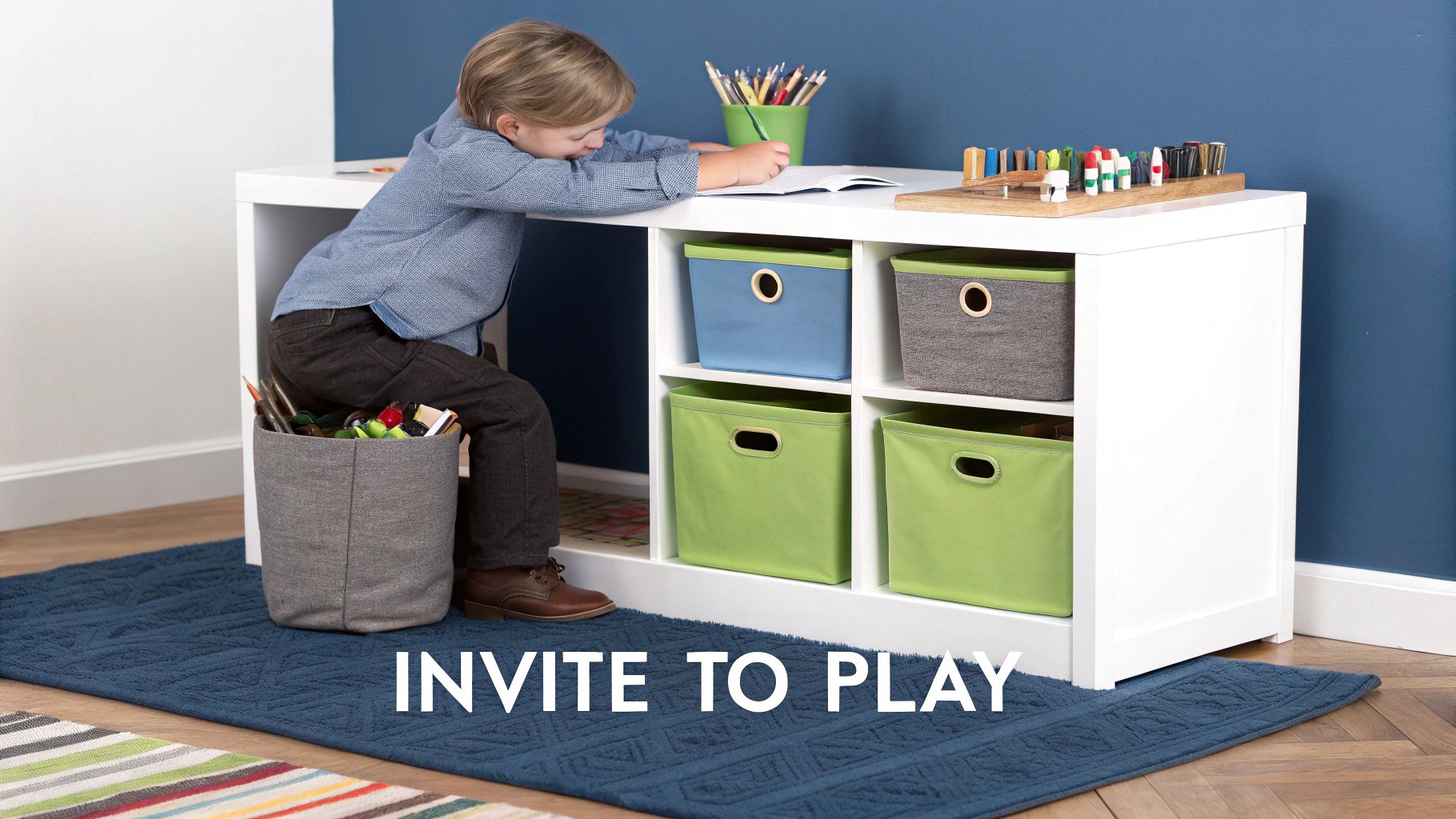 A young boy drawing at a white desk with colorful storage bins, surrounded by play items.