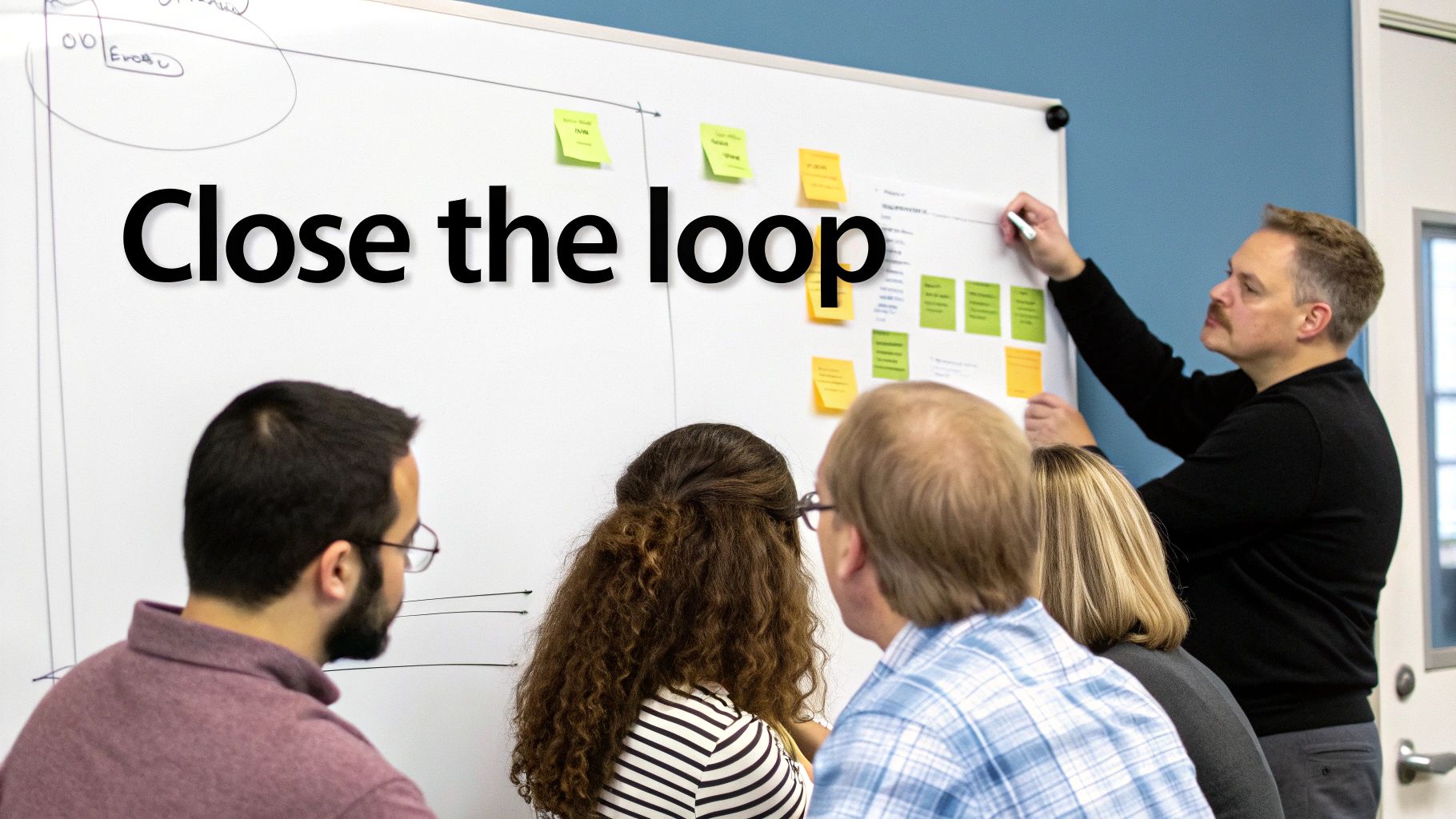 A man writes on a whiteboard covered with sticky notes during a collaborative meeting.