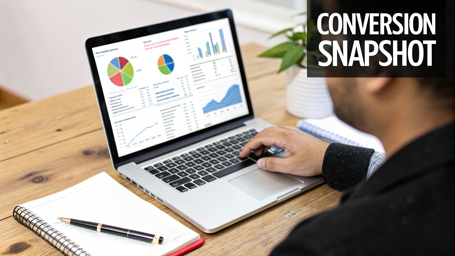 Person analyzing conversion data and charts on a laptop, with a notebook and pen on a wooden desk.