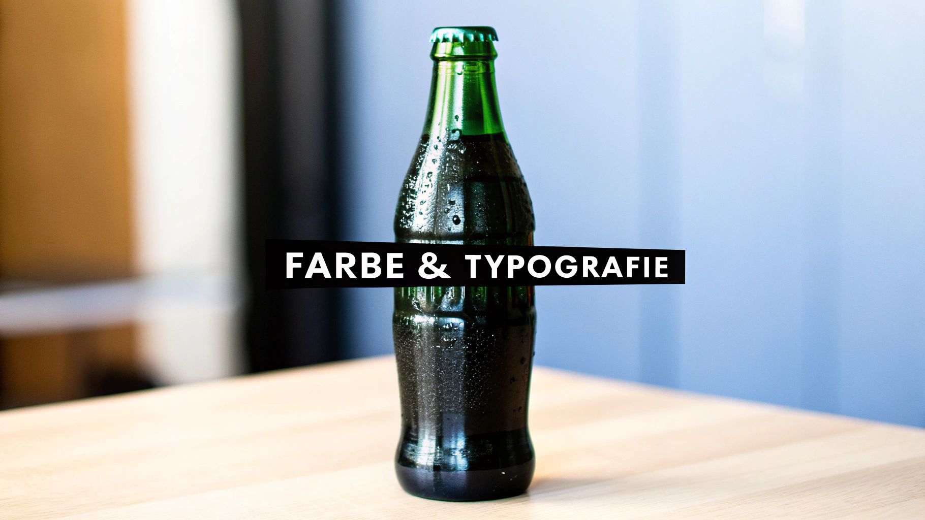 Eine grüne Flasche mit Wassertropfen auf einem Holztisch, quer überlagert von einer schwarzen Leiste mit weißer Schrift 'FARBE &amp; TYPOGRAFIE'.