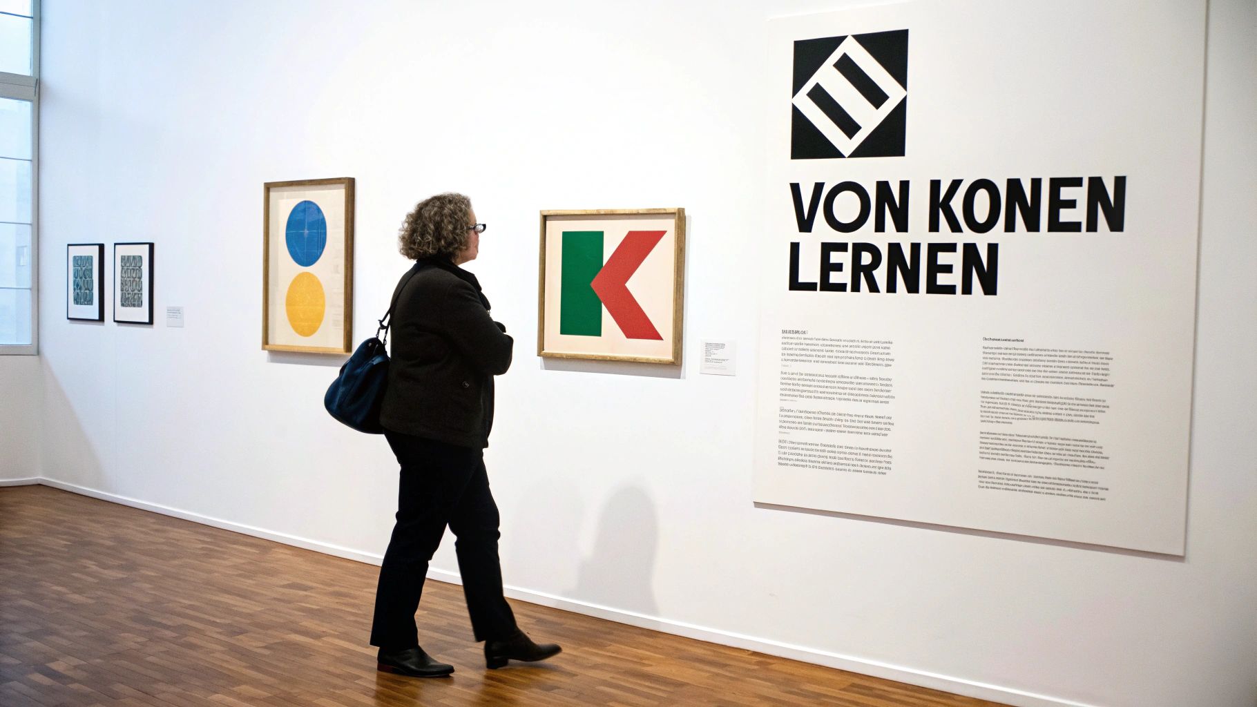 Eine Person betrachtet in einer Kunstgalerie ein abstraktes Gemälde mit einem roten K auf grünem Grund.