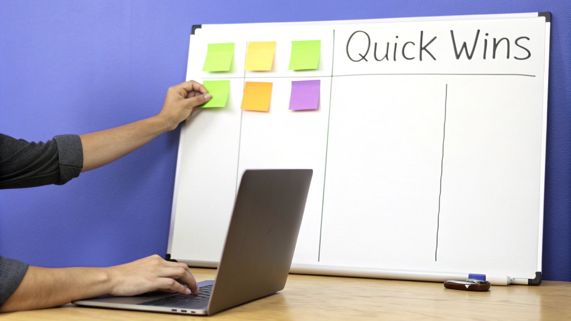Person placing sticky notes on Quick Wins board while working on laptop for strategic planning