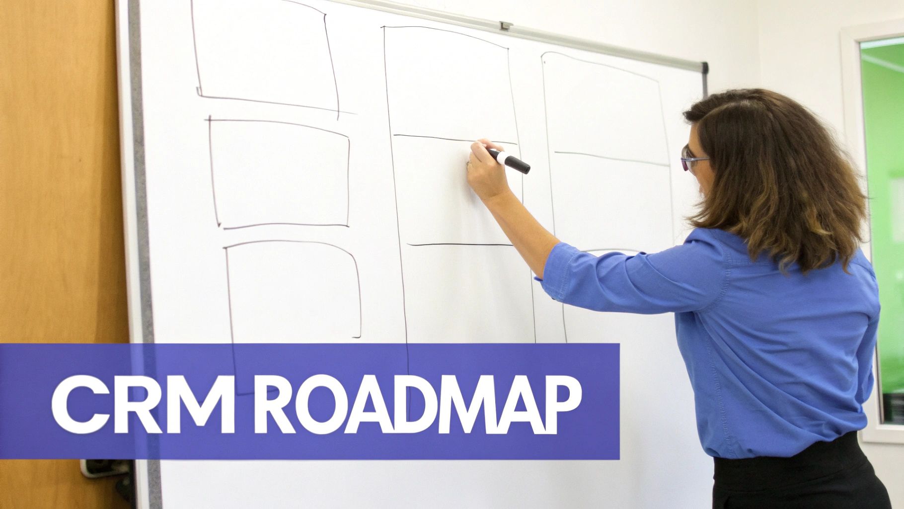 A woman in glasses writes on a whiteboard, sketching a CRM roadmap with drawn boxes.
