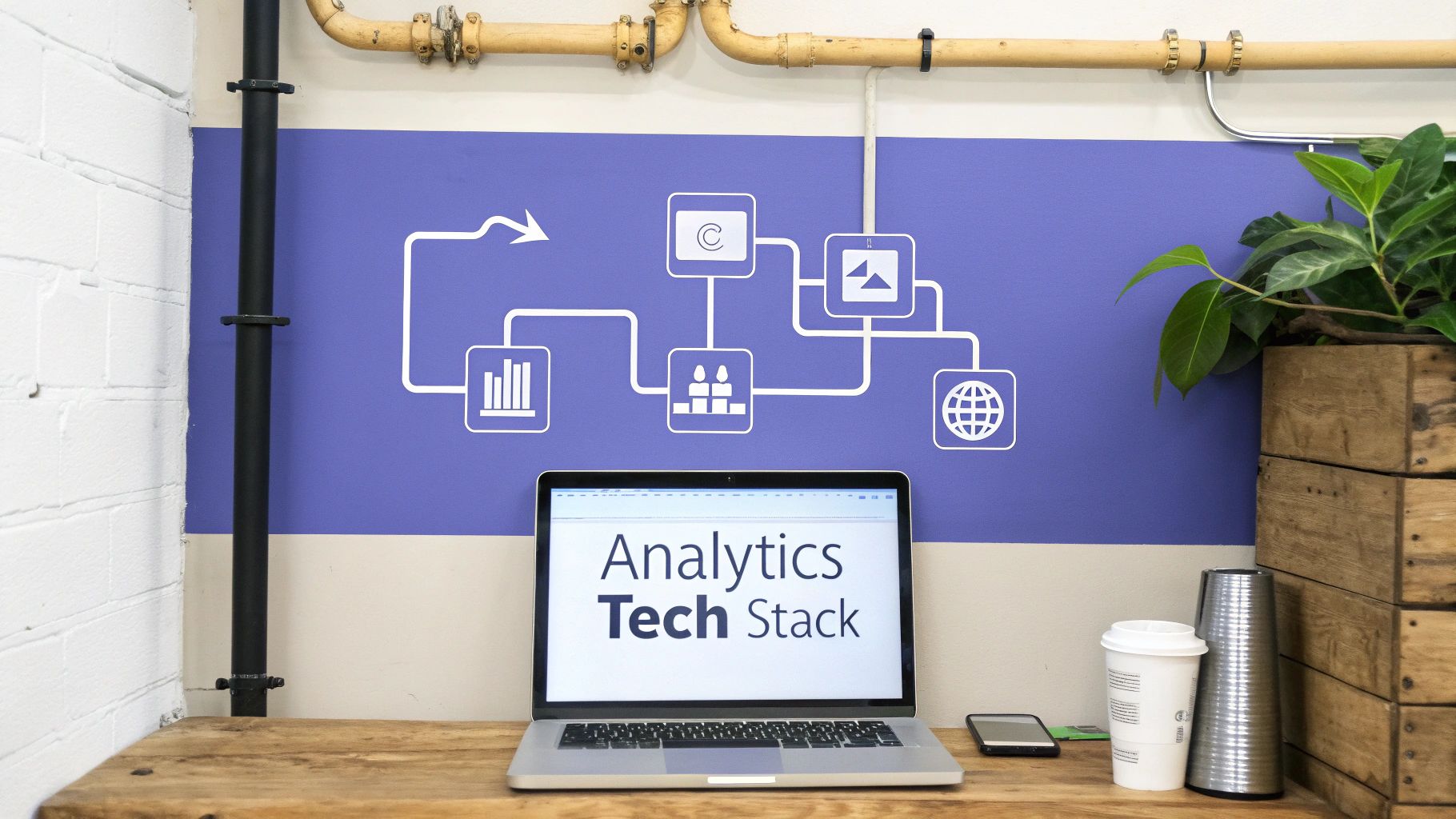 A laptop displaying 'Analytics Tech Stack' on a wooden desk with a data flow diagram on the wall.