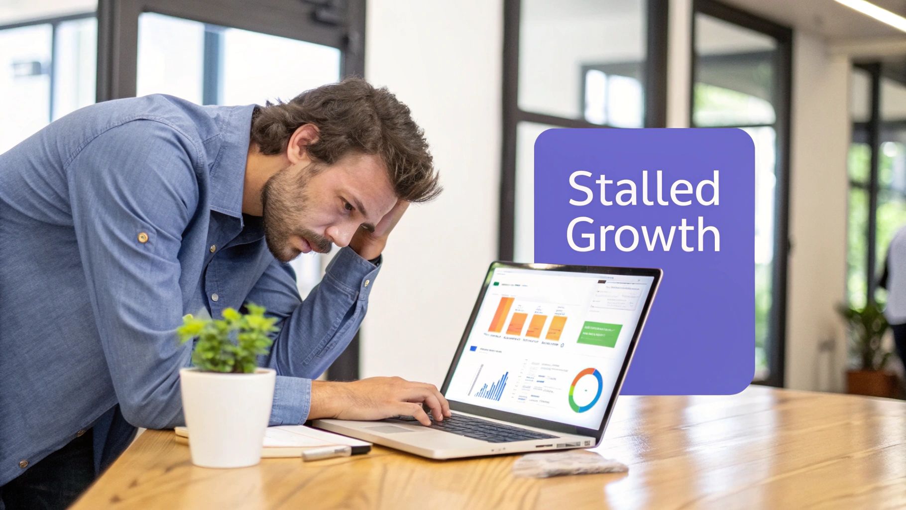 A worried man in a blue shirt looks at a laptop displaying 'Stalled Growth' data charts.