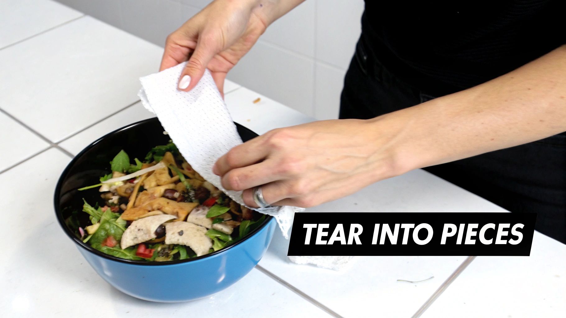 Shredded paper towels being mixed into a compost bin with food scraps and leaves.