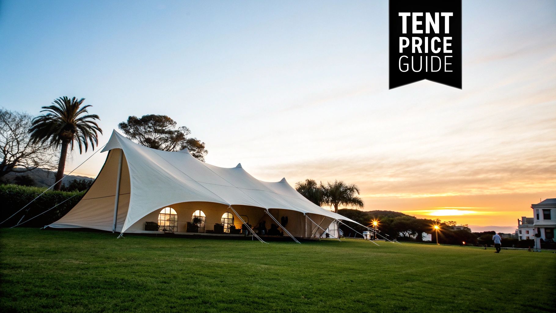 Large white stretch tent set up on a green lawn during a beautiful sunset.