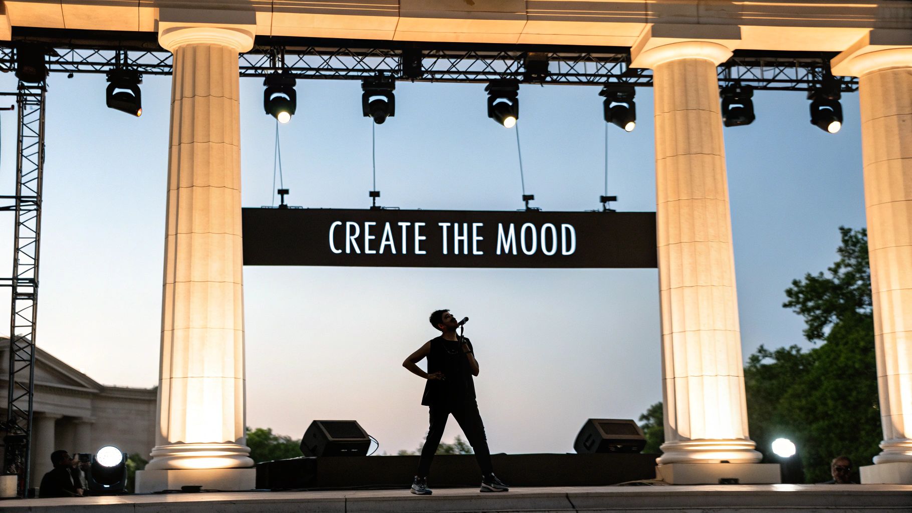 A silhouetted performer sings on an outdoor stage with 'CREATE THE MOOD' banner and illuminated columns.