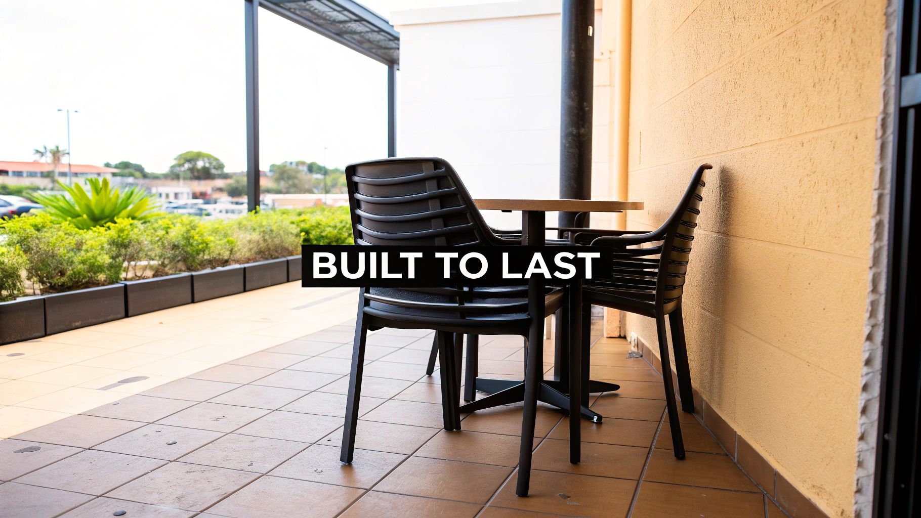Durable black outdoor patio chairs and wooden table on balcony with built to last text overlay
