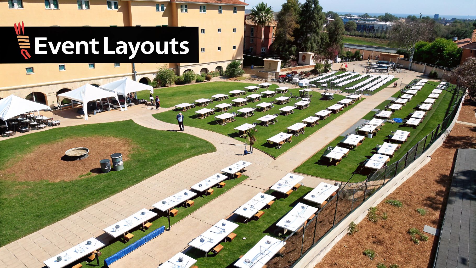 Aerial view of an outdoor event layout with numerous long folding tables on grass and paved paths, with tents and rows of chairs.