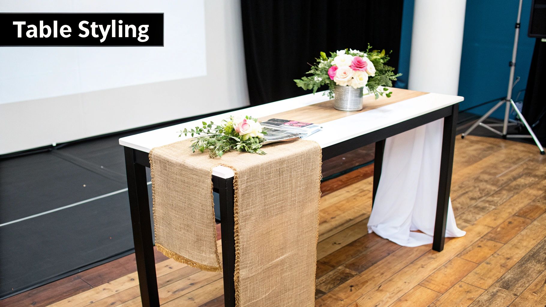 A styled rectangular cocktail table with a burlap runner, floral arrangements, and a magazine.