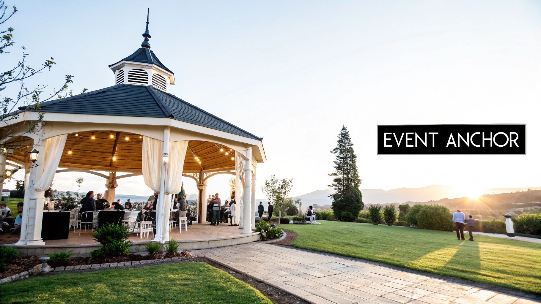 People enjoy an outdoor event in a beautifully decorated gazebo at sunset, overlooking hills.
