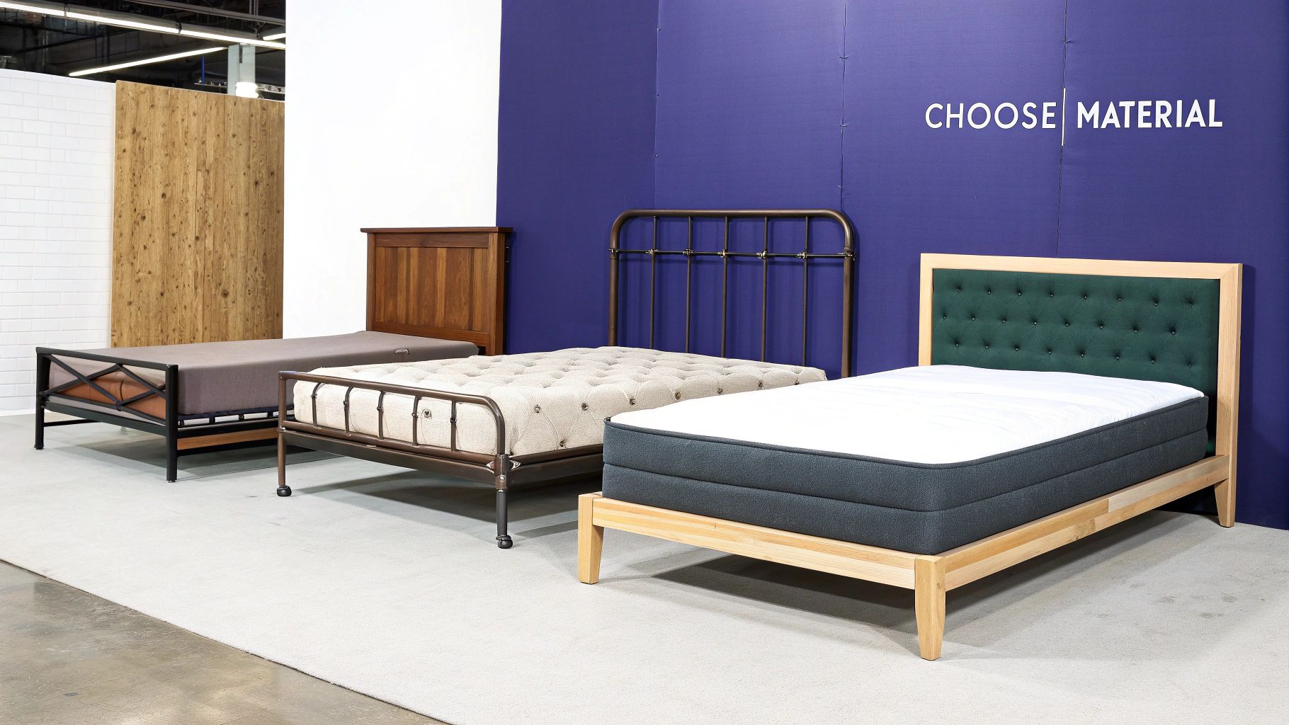 Three diverse queen size bed frames with different headboards and mattresses displayed in a showroom.