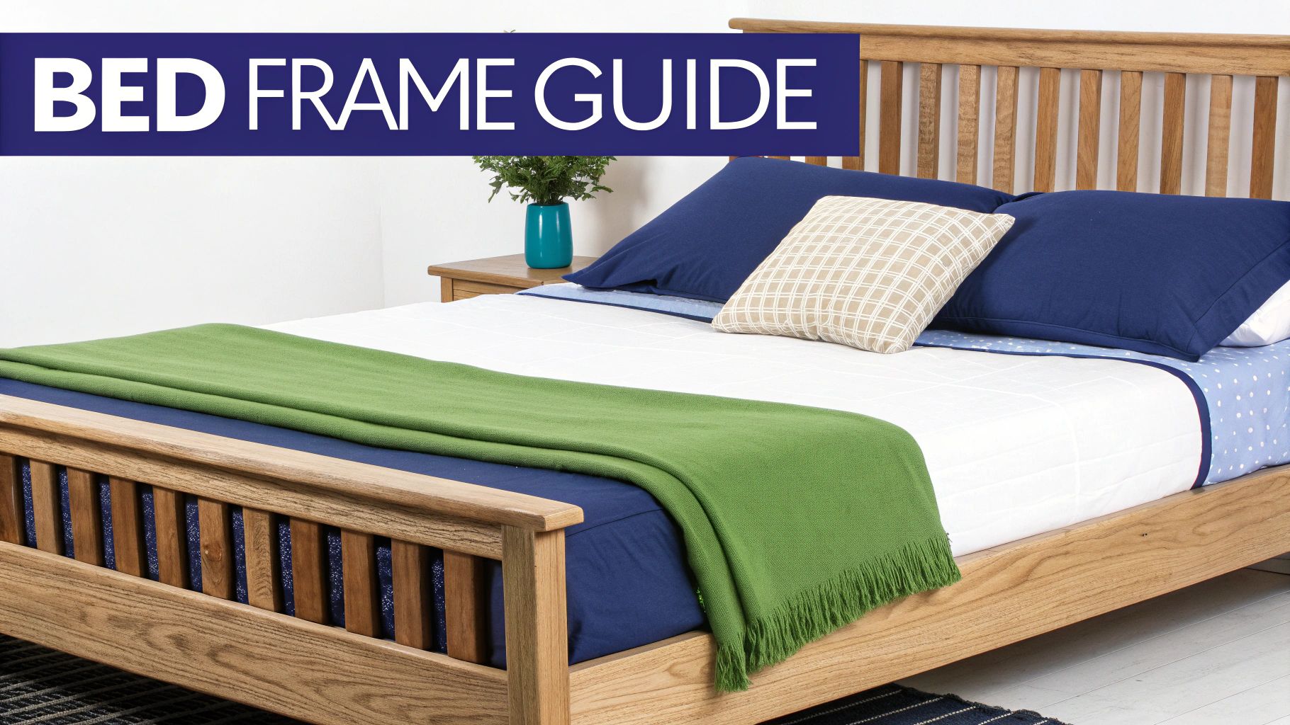 A light wooden bed frame with a mattress, blue pillows, a white quilt, and a green throw blanket in a bedroom.