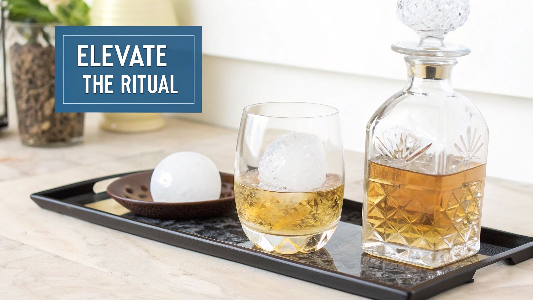 A crystal whiskey decanter, a glass with a large ice ball, and another ice ball on a tray.