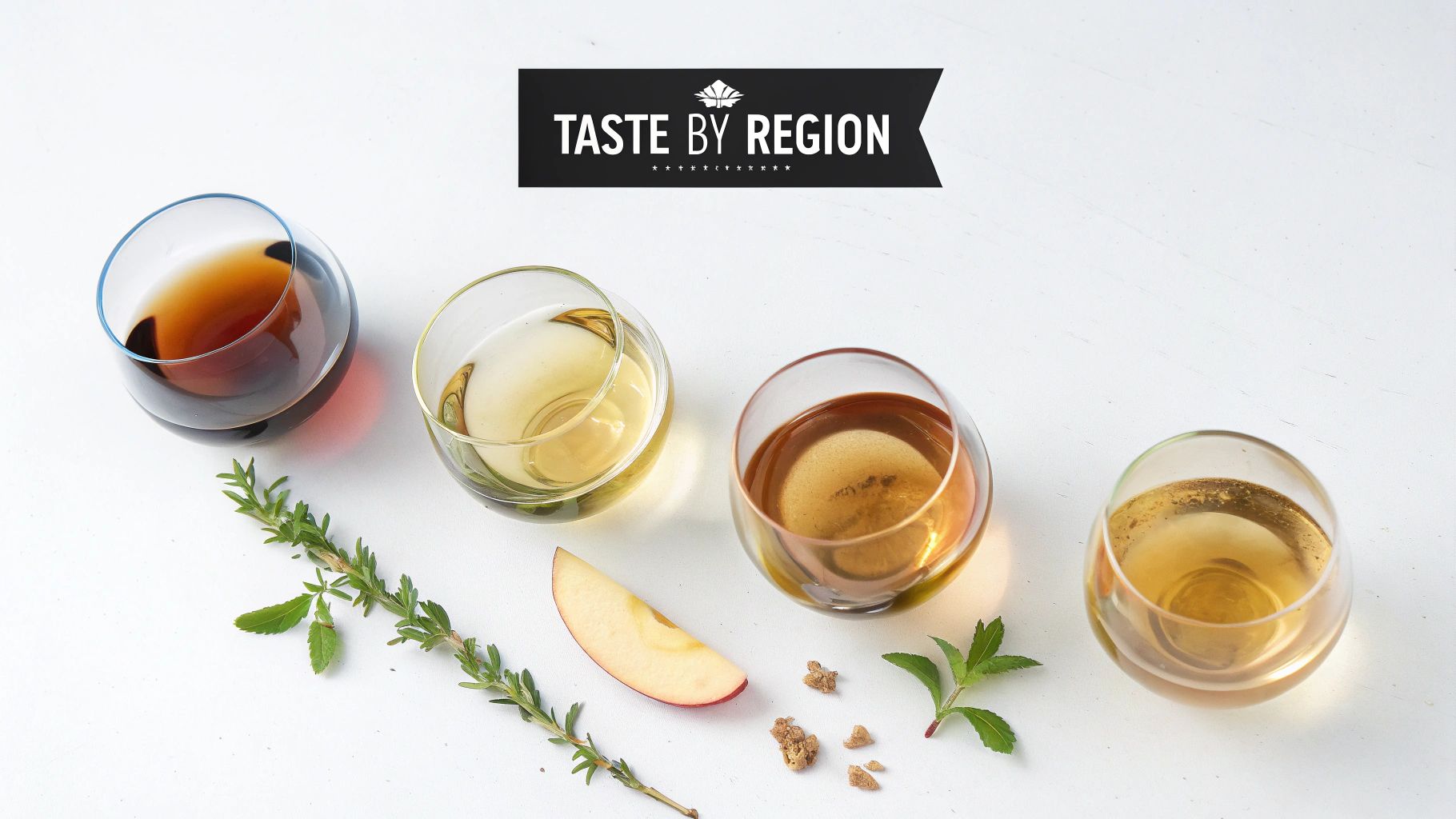 Four glasses of regional beverages with herbs and apple on a white background, promoting 'Taste by Region'.