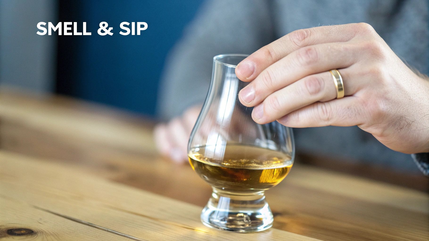 A close-up of a hand holding a whiskey glass, swirling the amber liquid