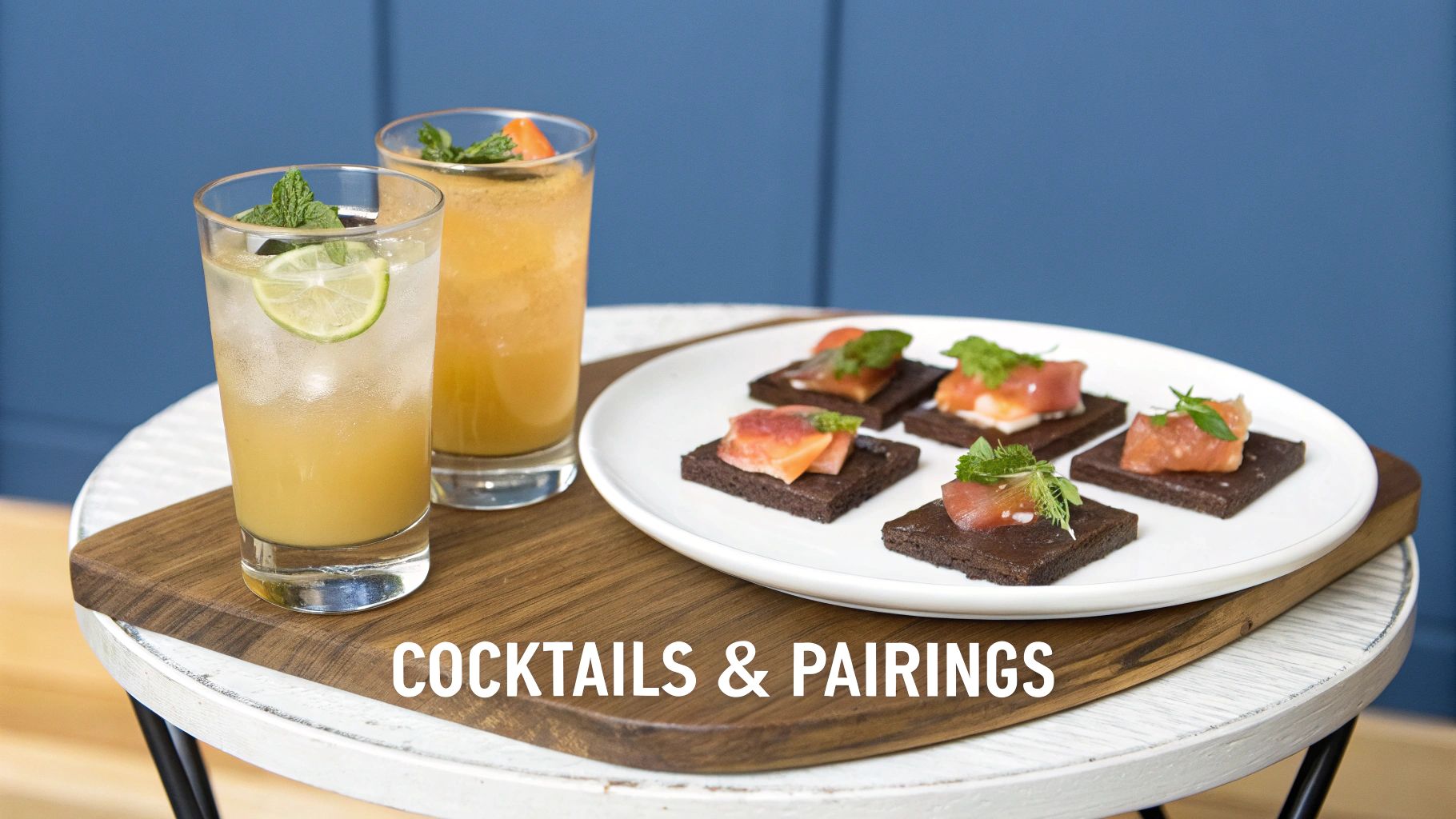 Two refreshing cocktails, one with lime and mint, paired with five salmon appetizers on dark crackers.