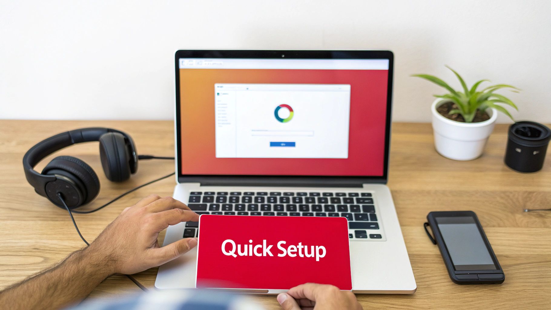 A person initiates a quick setup on a red device in front of a laptop with headphones and a plant.