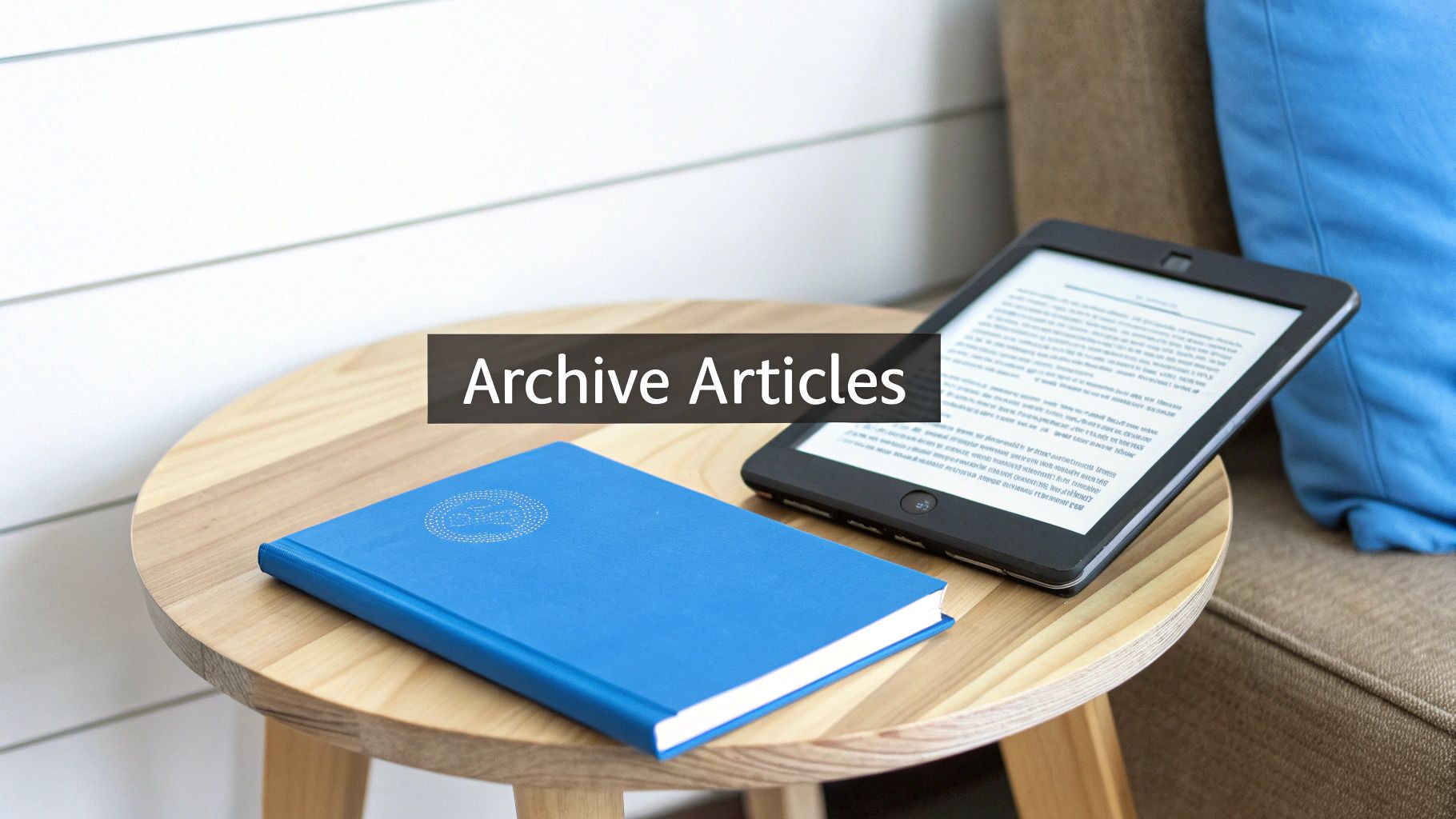 A blue notebook and an e-reader on a round wooden table, with text 'Archive Articles' overlaid.