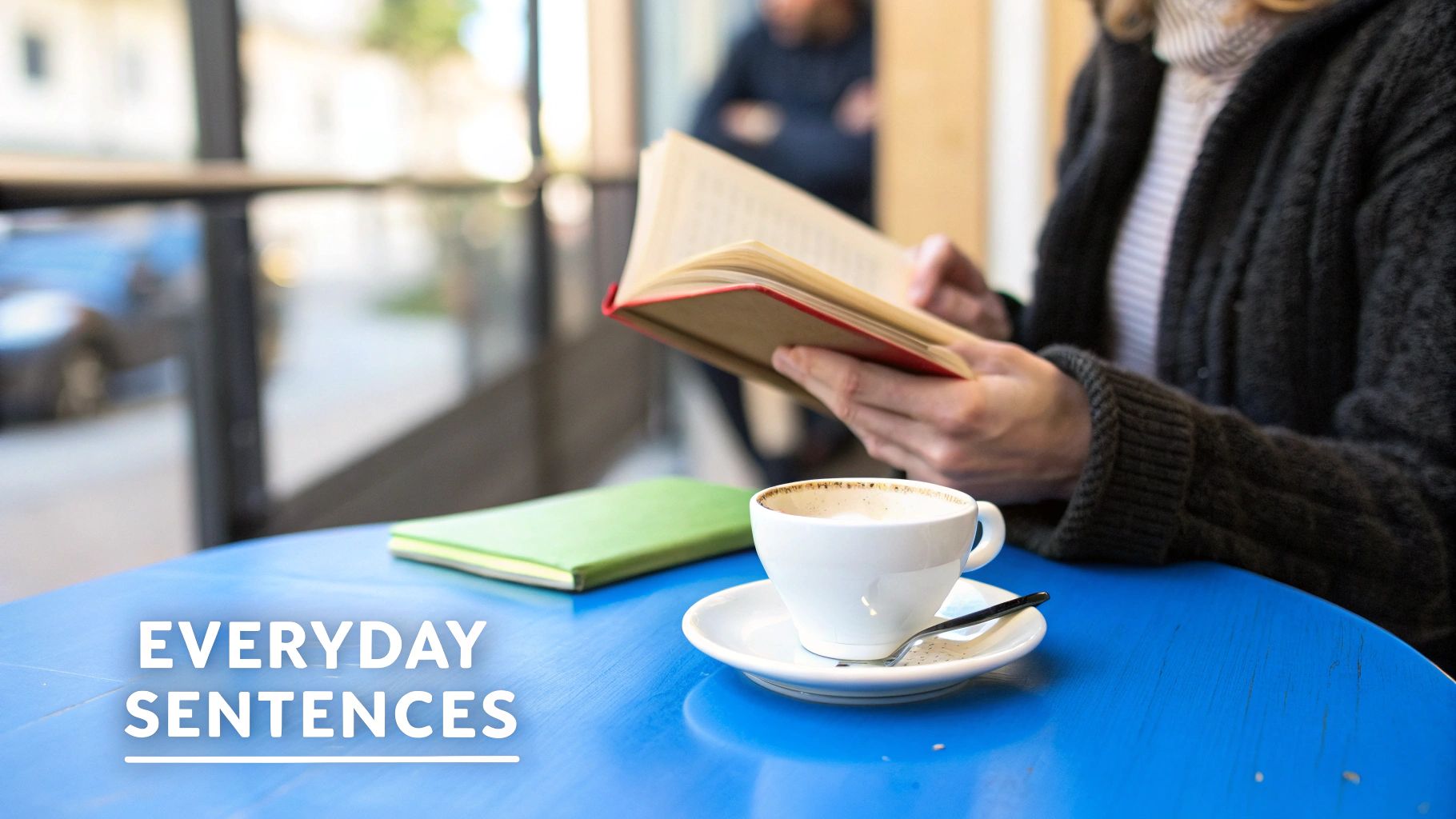 Человек читает книгу за синим столиком в кафе рядом с чашкой кофе и зелёной тетрадью.