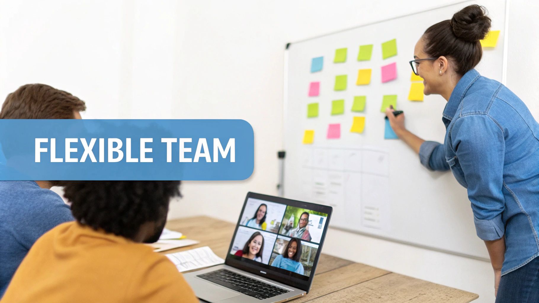 A diverse flexible team collaborates in a hybrid meeting, with some members in-person and others on a video call.