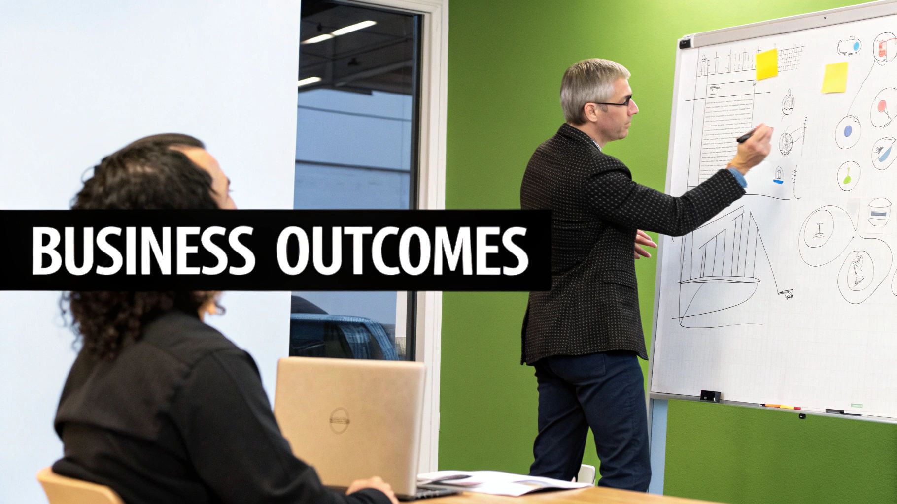 A business consultant explains complex data concepts on a whiteboard to a colleague during a strategy session.