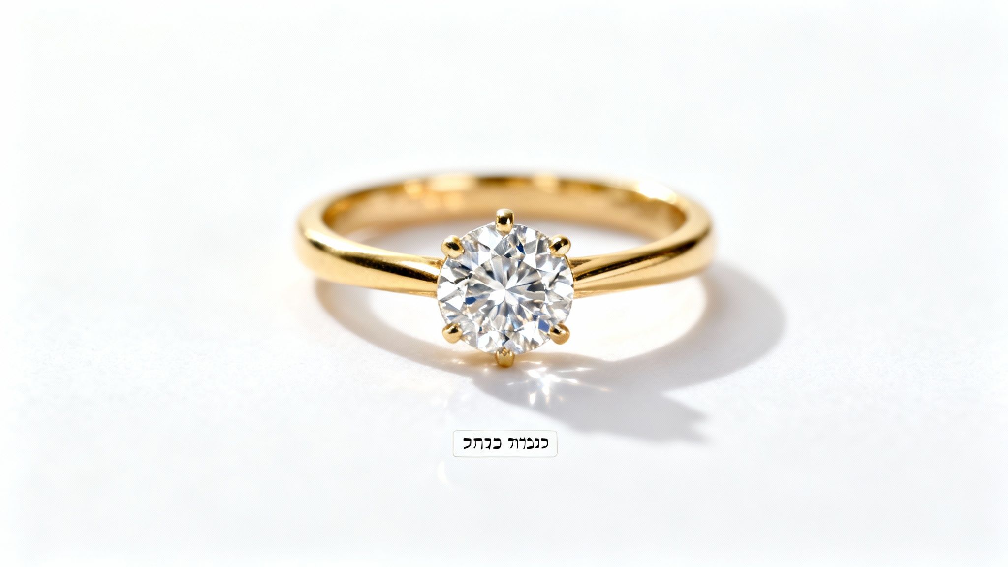 טבעת אירוסין מזהב צהוב עם יהלום עגול נוצץ, מונחת על רקע לבן עם צל עדין.