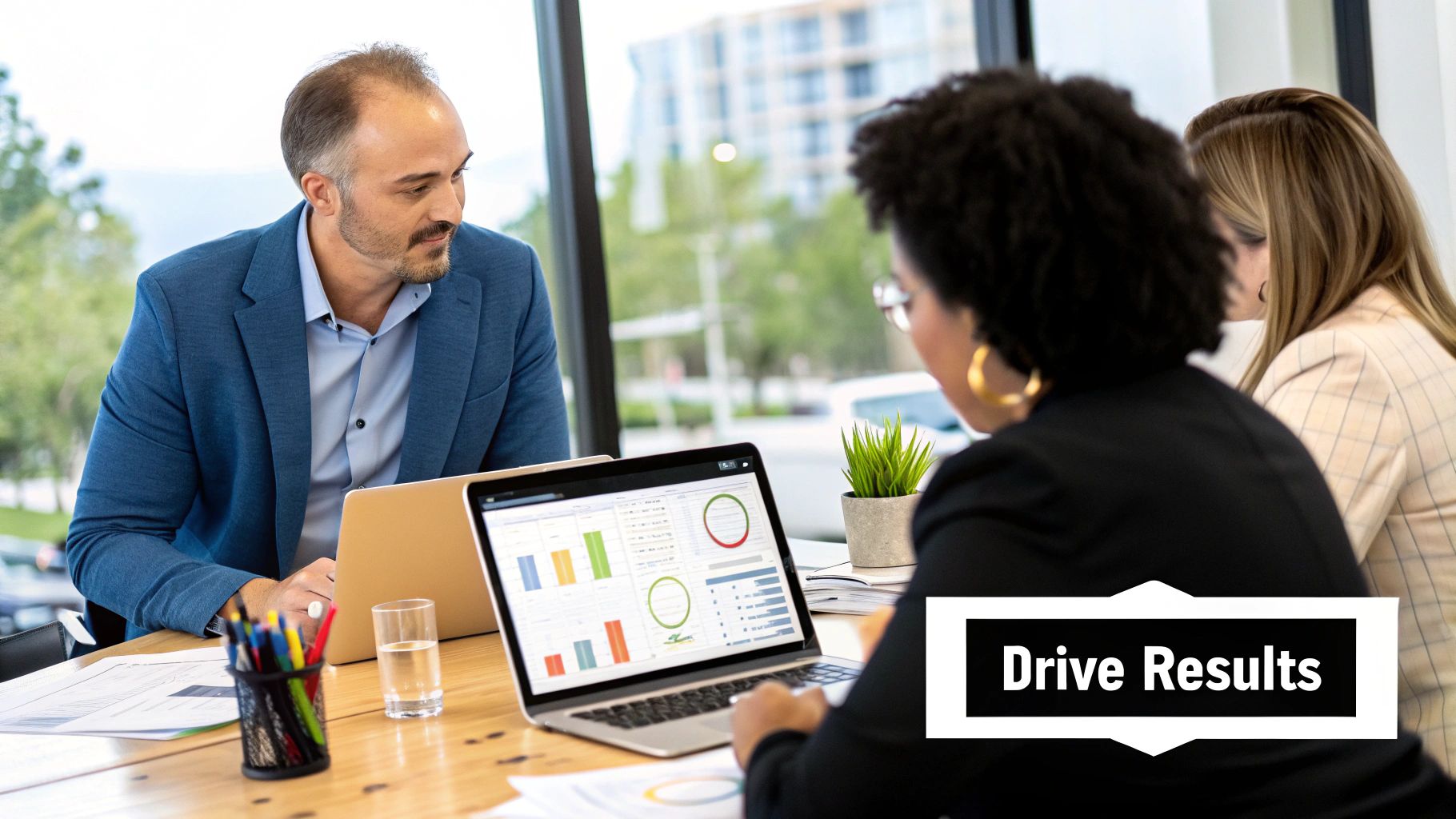 Three business professionals collaborating in an office, reviewing data and charts on a laptop.