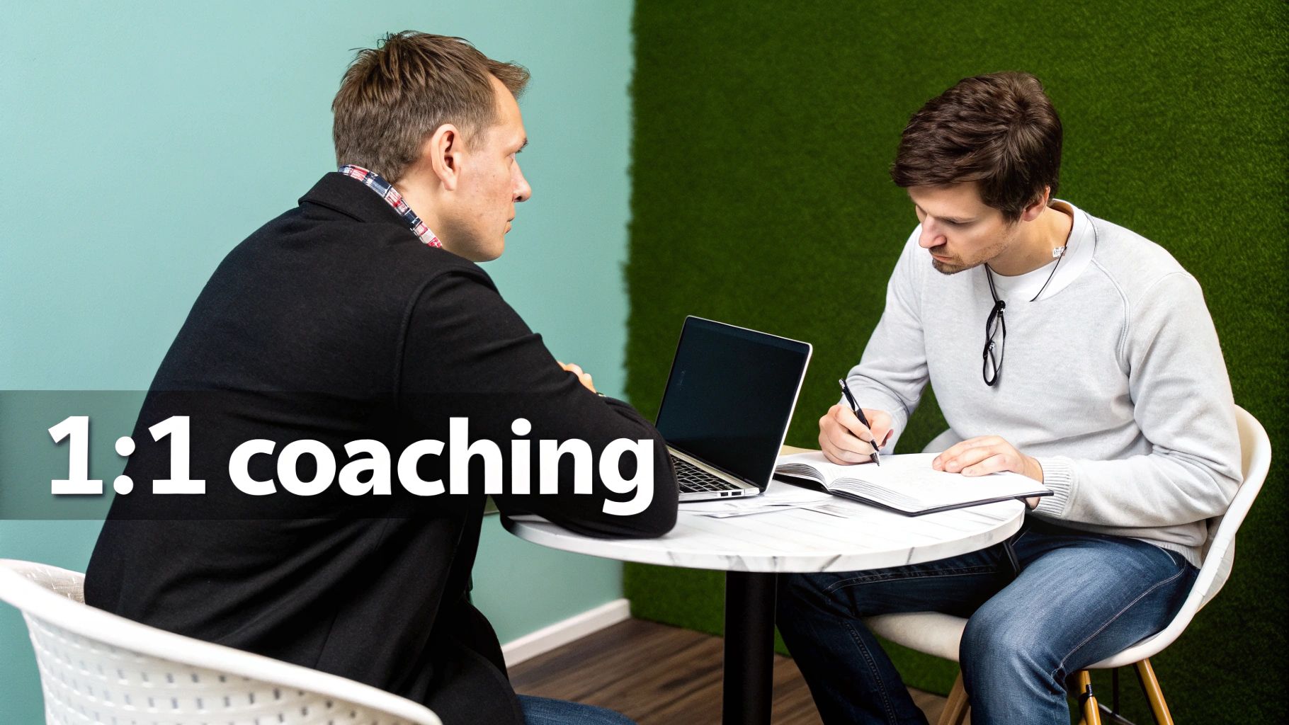 Professional one-on-one coaching session with two men, one writing and one listening.