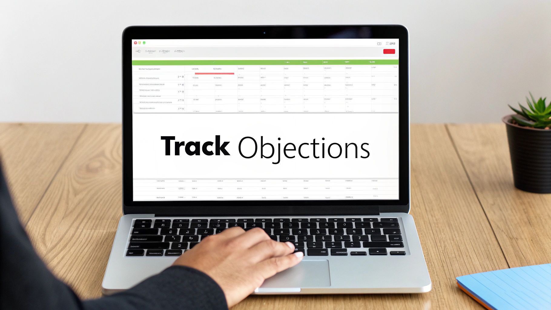 A person's hands typing on a laptop screen displaying a 'Track Objections' spreadsheet interface.