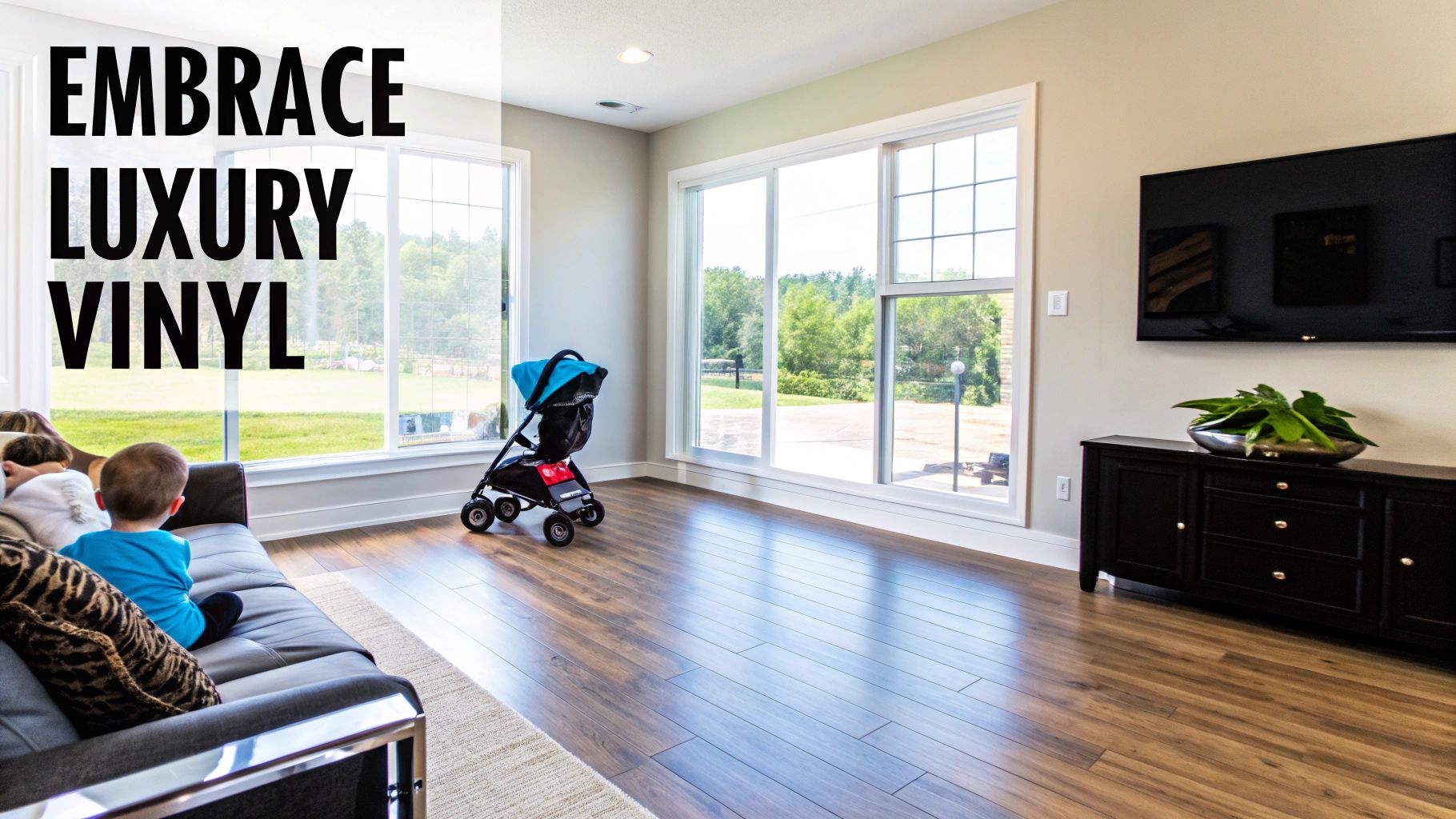 A bright living room featuring wood-look luxury vinyl flooring, large windows, a sofa, a baby stroller, and a mounted TV.