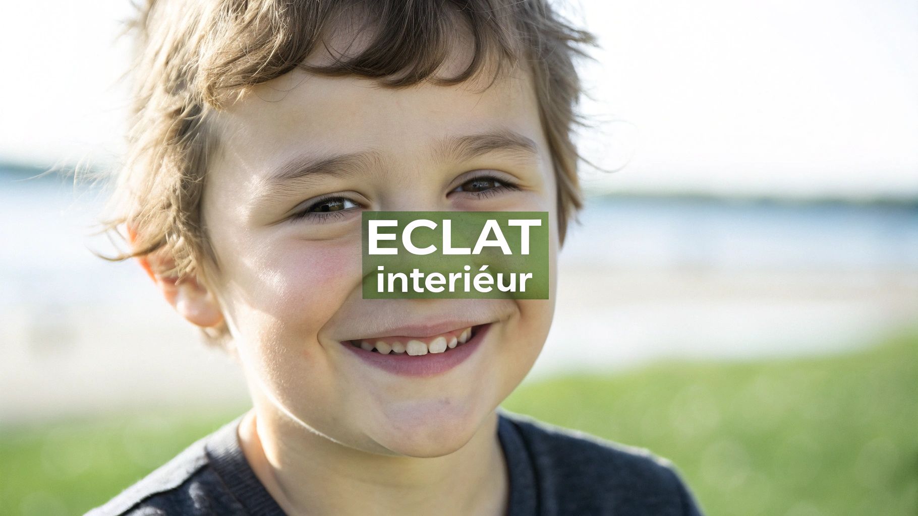 Gros plan sur le visage joyeux d'un jeune garçon souriant, avec le texte "ECLAT intérieur" affiché au centre.