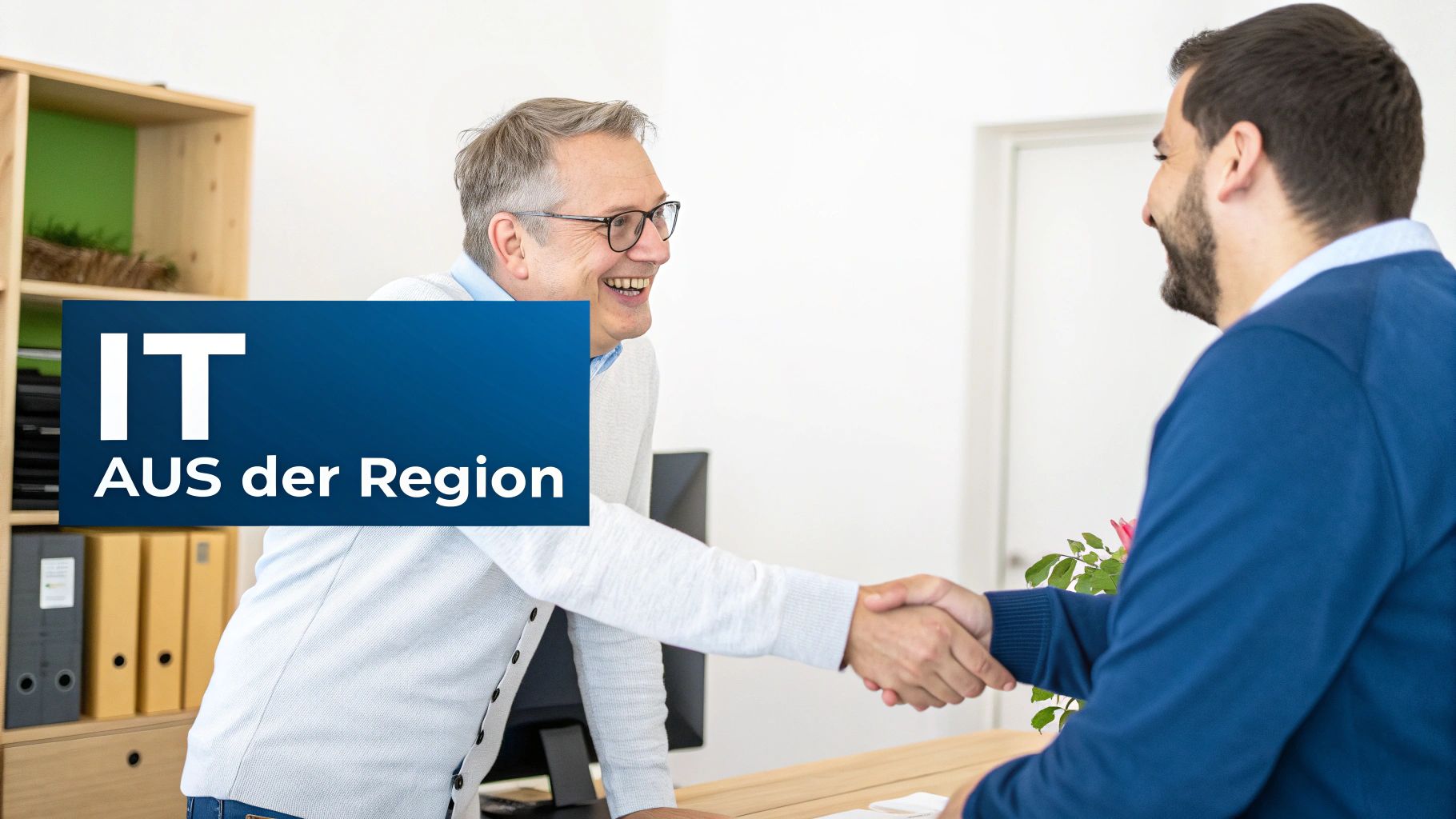 Zwei lächelnde Männer schütteln sich die Hände in einem Büro, mit Text 'IT AUS der Region' auf blauem Hintergrund.