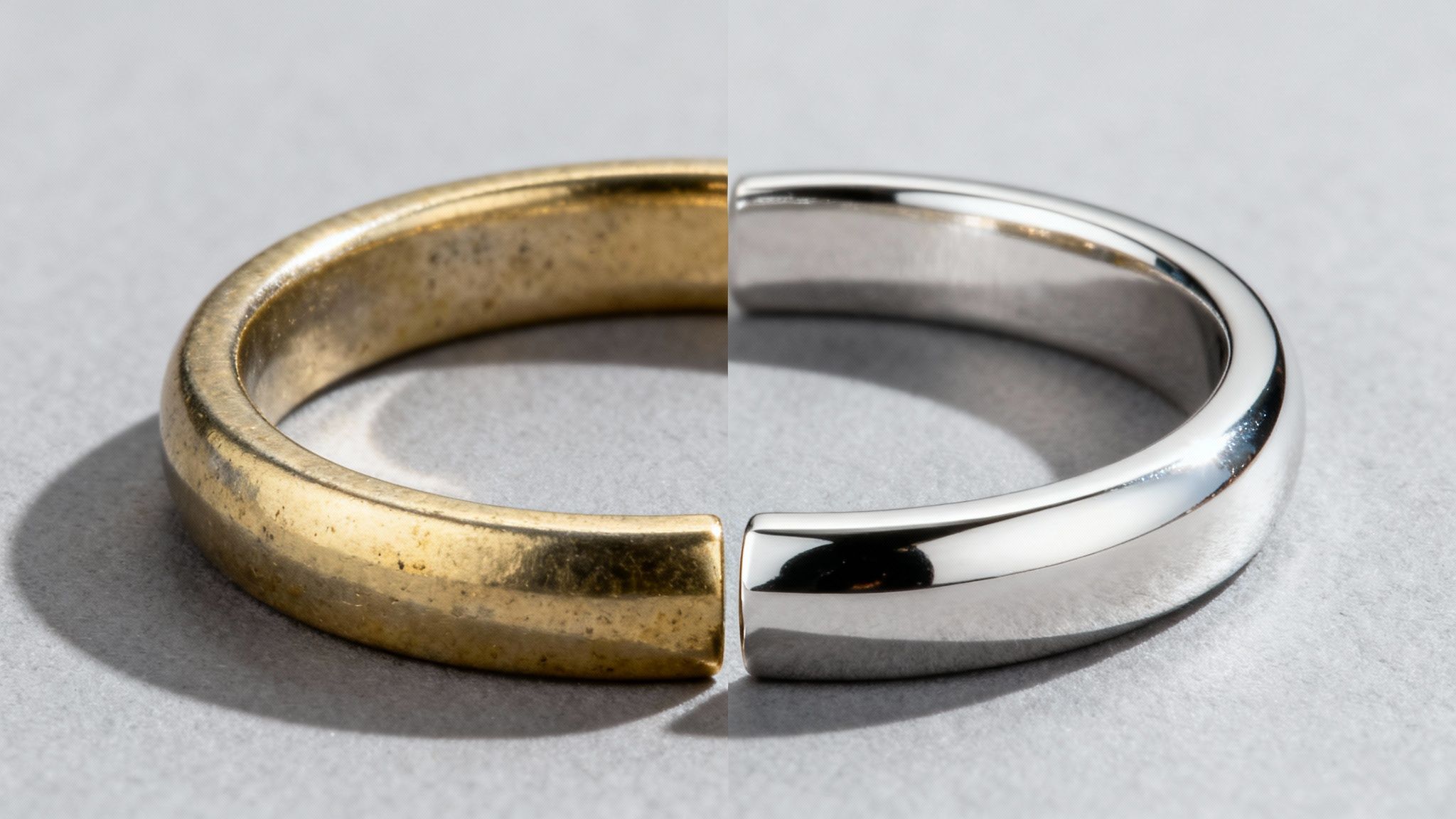 A ring split in half, one side tarnished gold and the other shiny rhodium-plated silver, showcasing transformation.