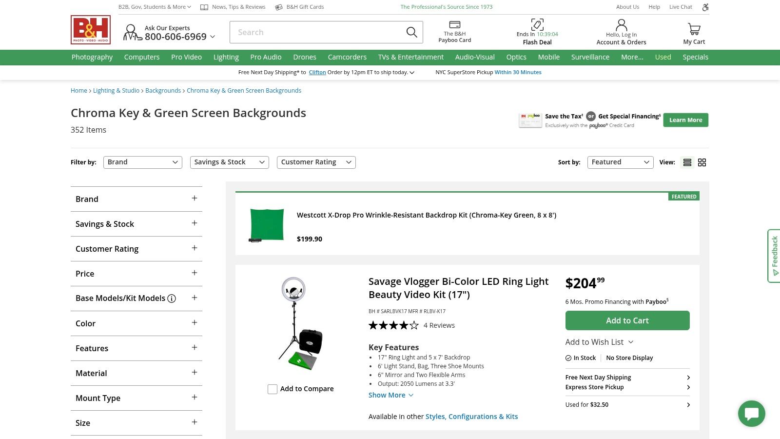 A person setting up a physical green screen backdrop purchased from a retailer like B&H Photo Video.