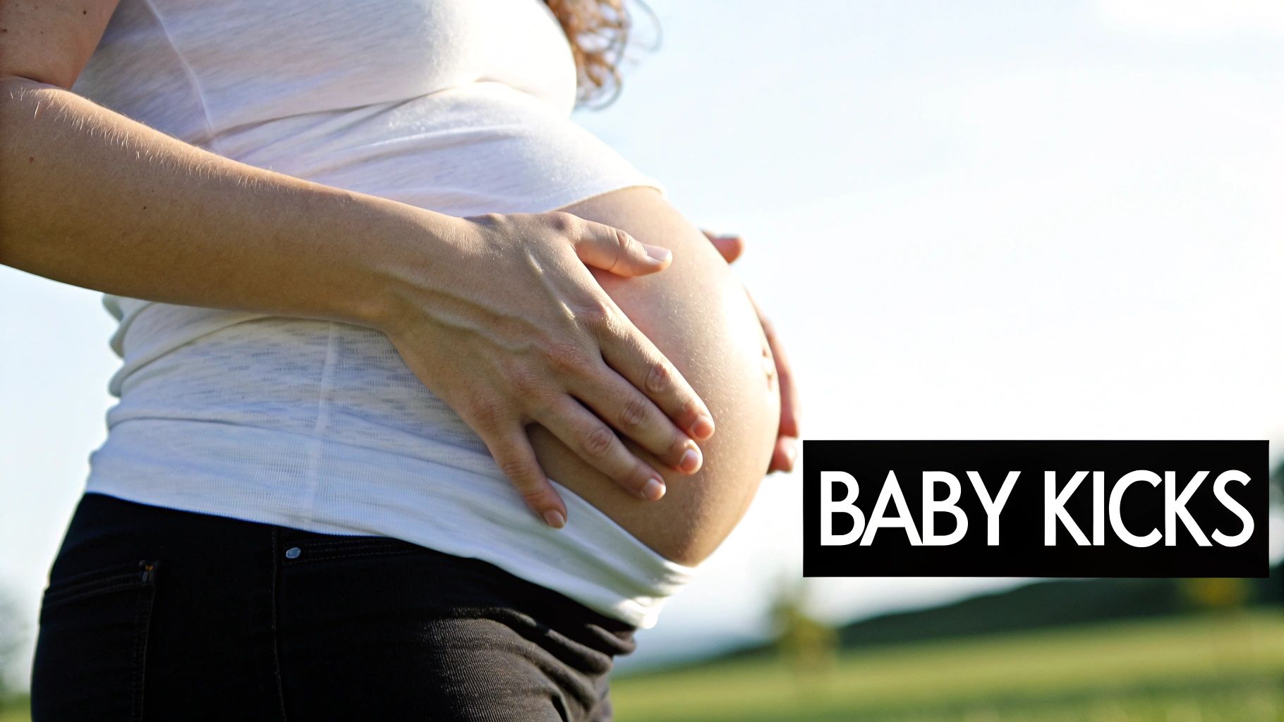 A happy pregnant woman touching her belly in a bright, sunny room.