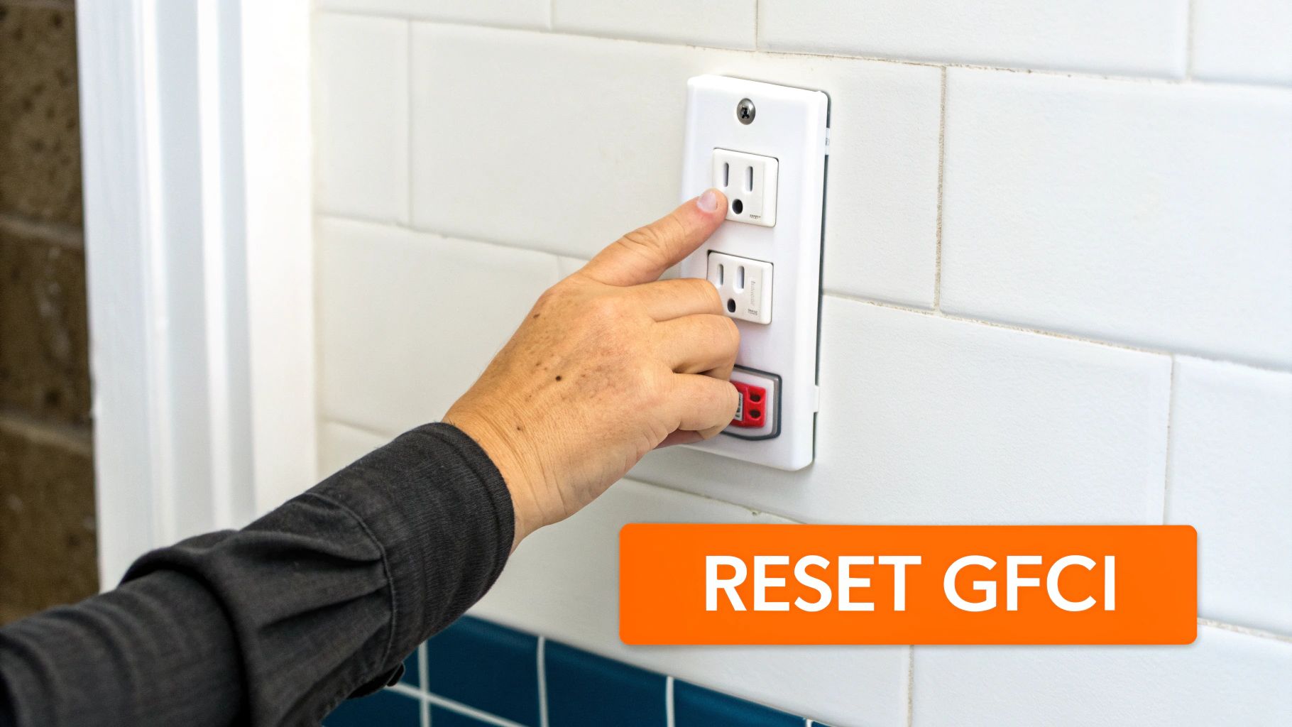 A person's hand presses the reset button on a white GFCI electrical outlet.