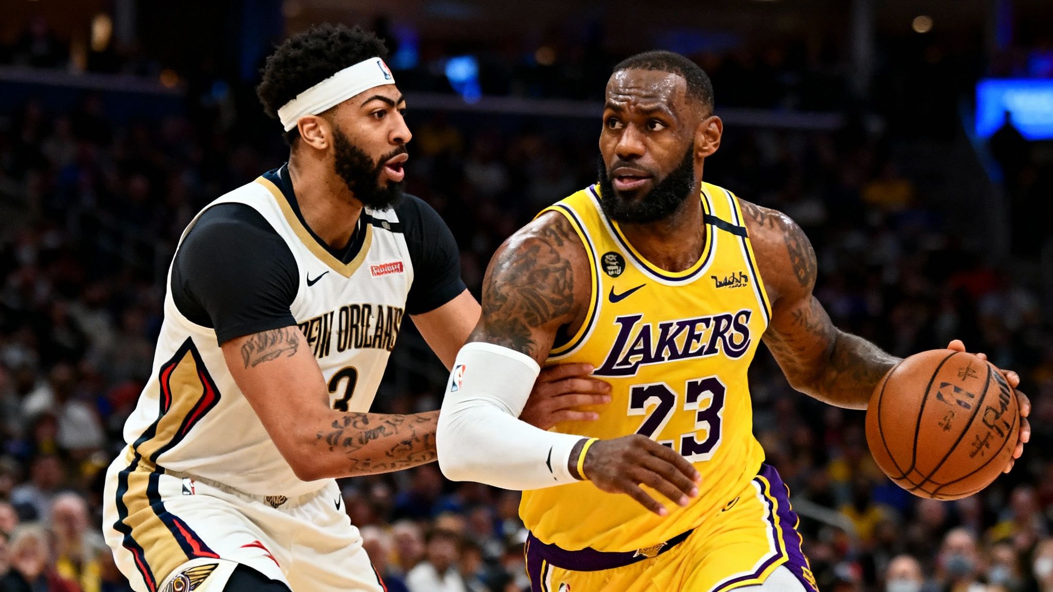 | A New Orleans Pelicans player attempts to score against a Los Angeles Lakers defender in a dynamic on-court action shot.