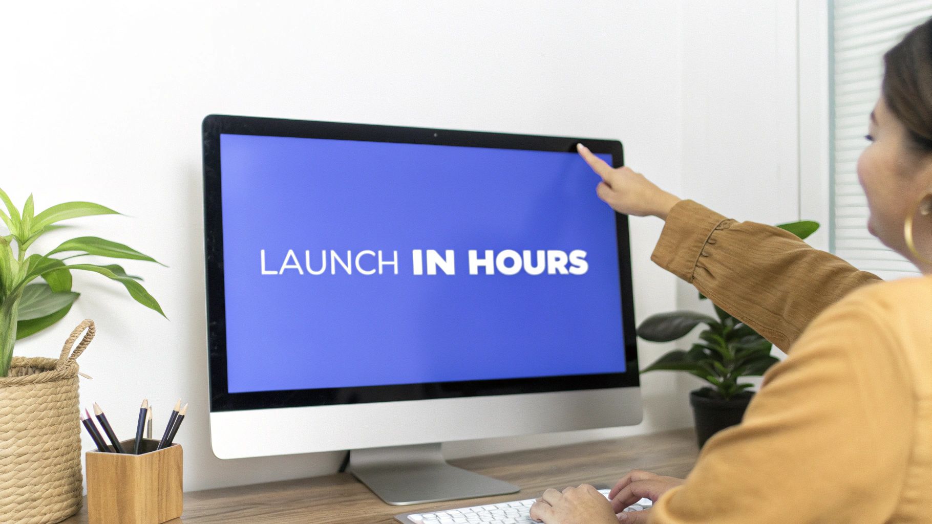 A woman points at a computer screen displaying 'LAUNCH IN HOURS' at a modern desk.