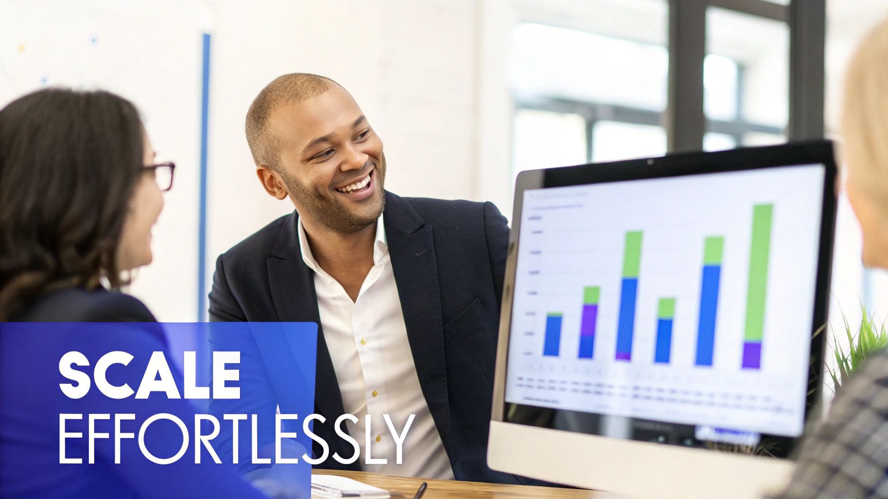A smiling businessman discusses data on a computer screen with colleagues in a modern office.