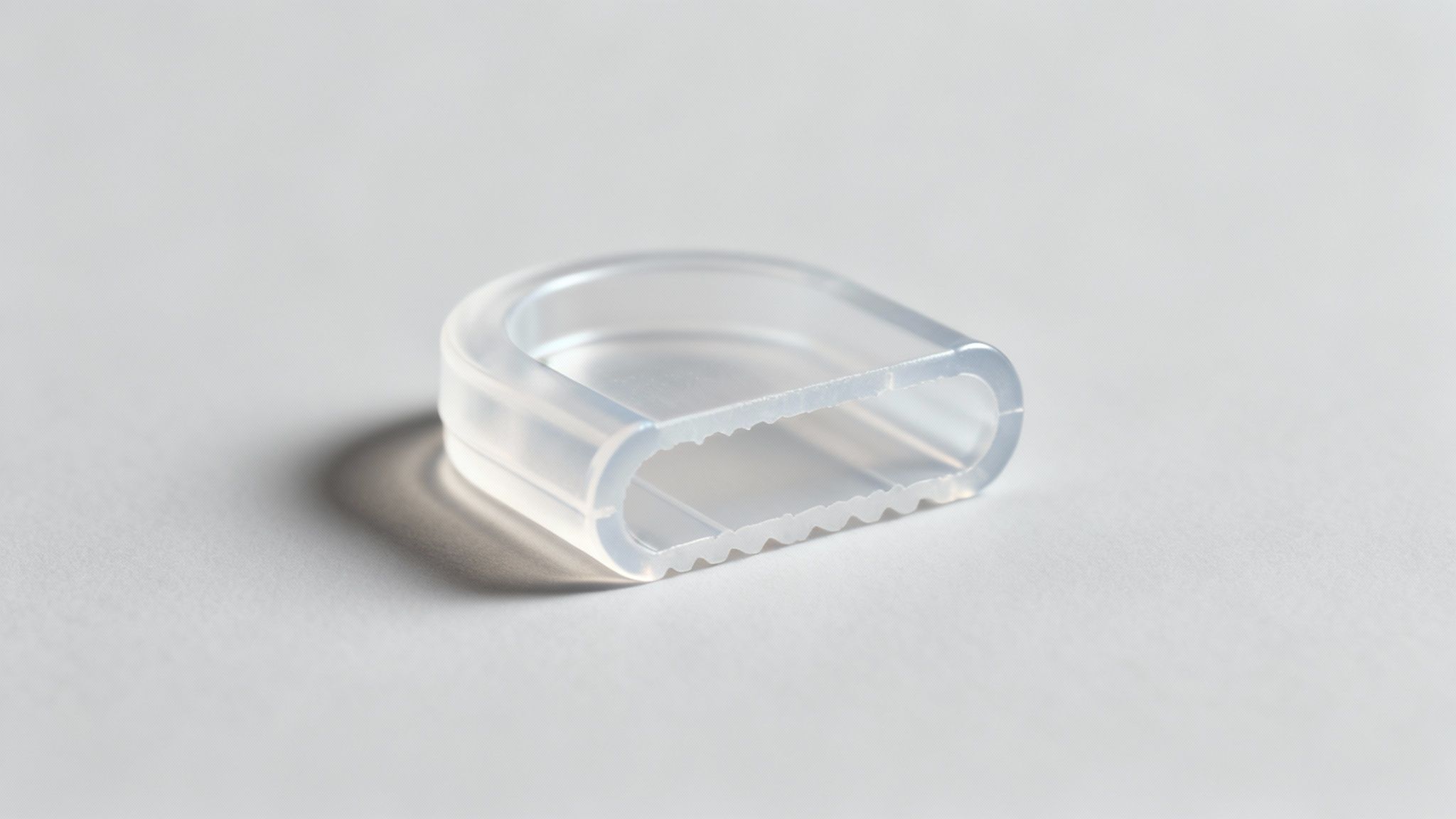Close-up of a translucent, U-shaped plastic clip with serrated interior edges on a white background.