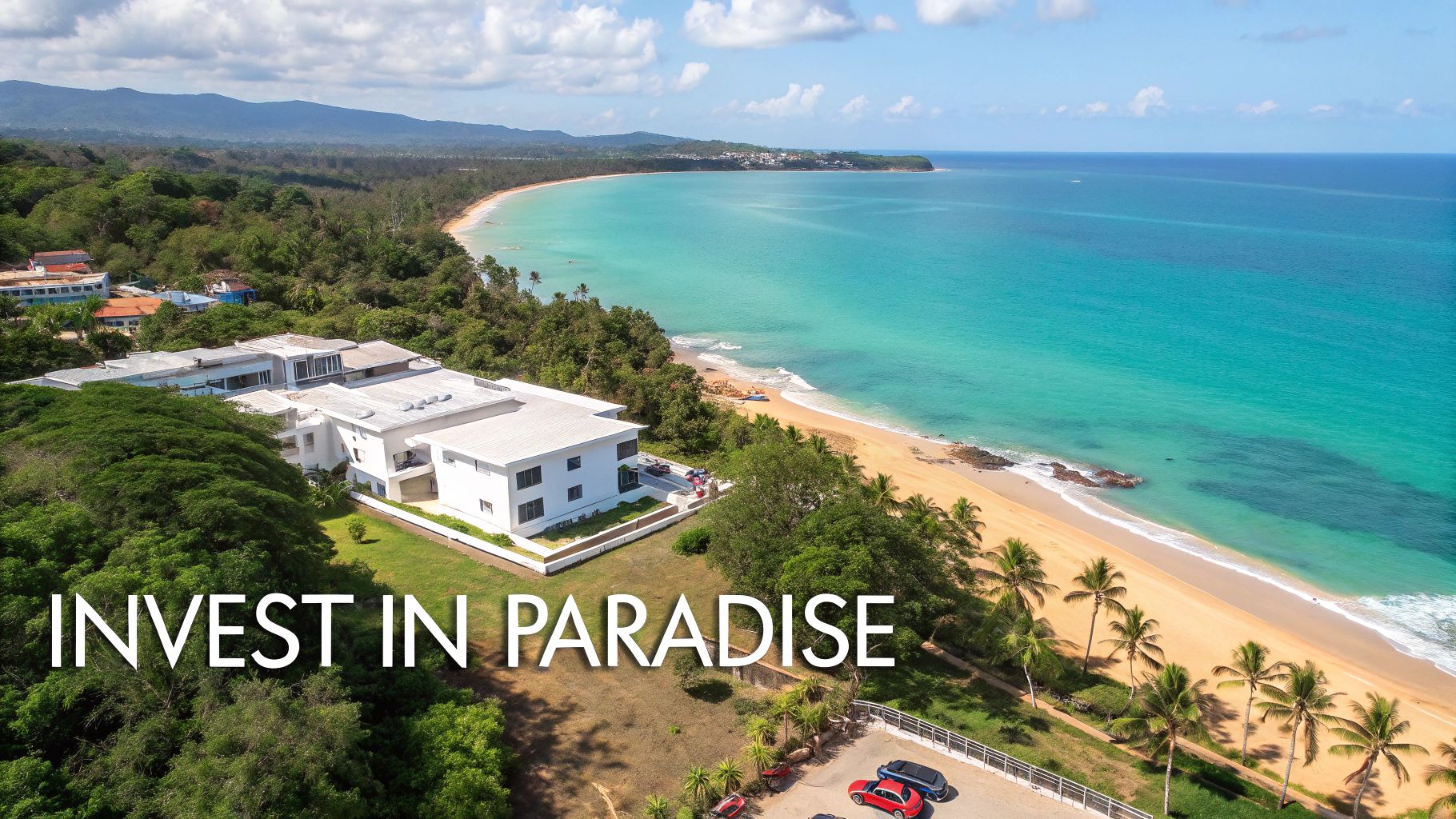 Vista aérea de un edificio moderno blanco junto a una impresionante playa tropical con océano turquesa.