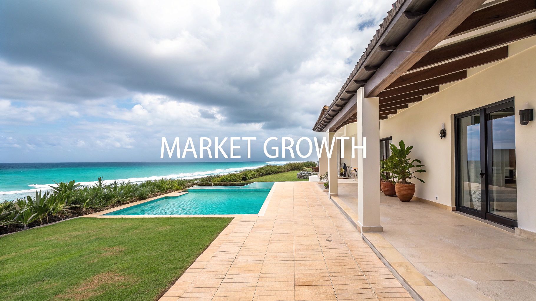 Una impresionante villa frente a la playa con una piscina infinita, un exuberante césped verde y un océano turquesa bajo un cielo nublado.