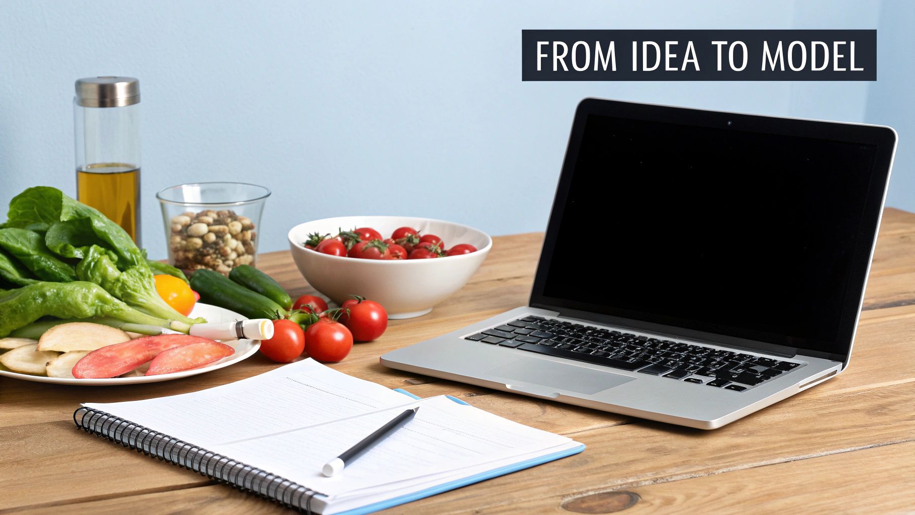 A workspace featuring healthy food, a laptop, and a notebook with a banner stating 'FROM IDEA TO MODEL'.