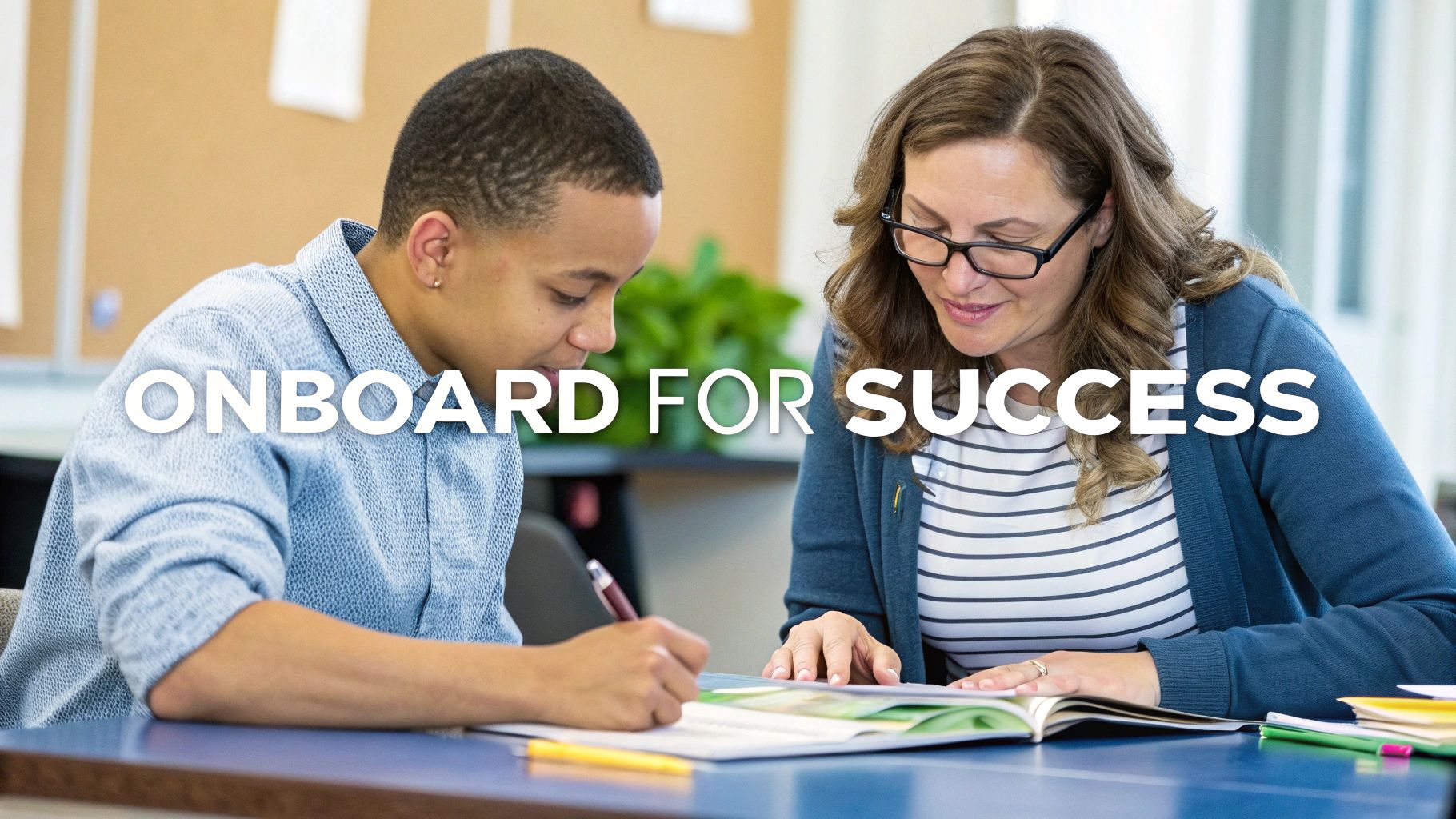 A mentor and student collaborate at a desk, reviewing materials and writing for success.