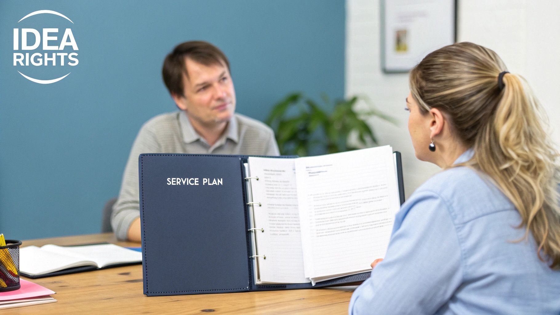 Two people discuss a service plan in a meeting, with a woman holding the binder.