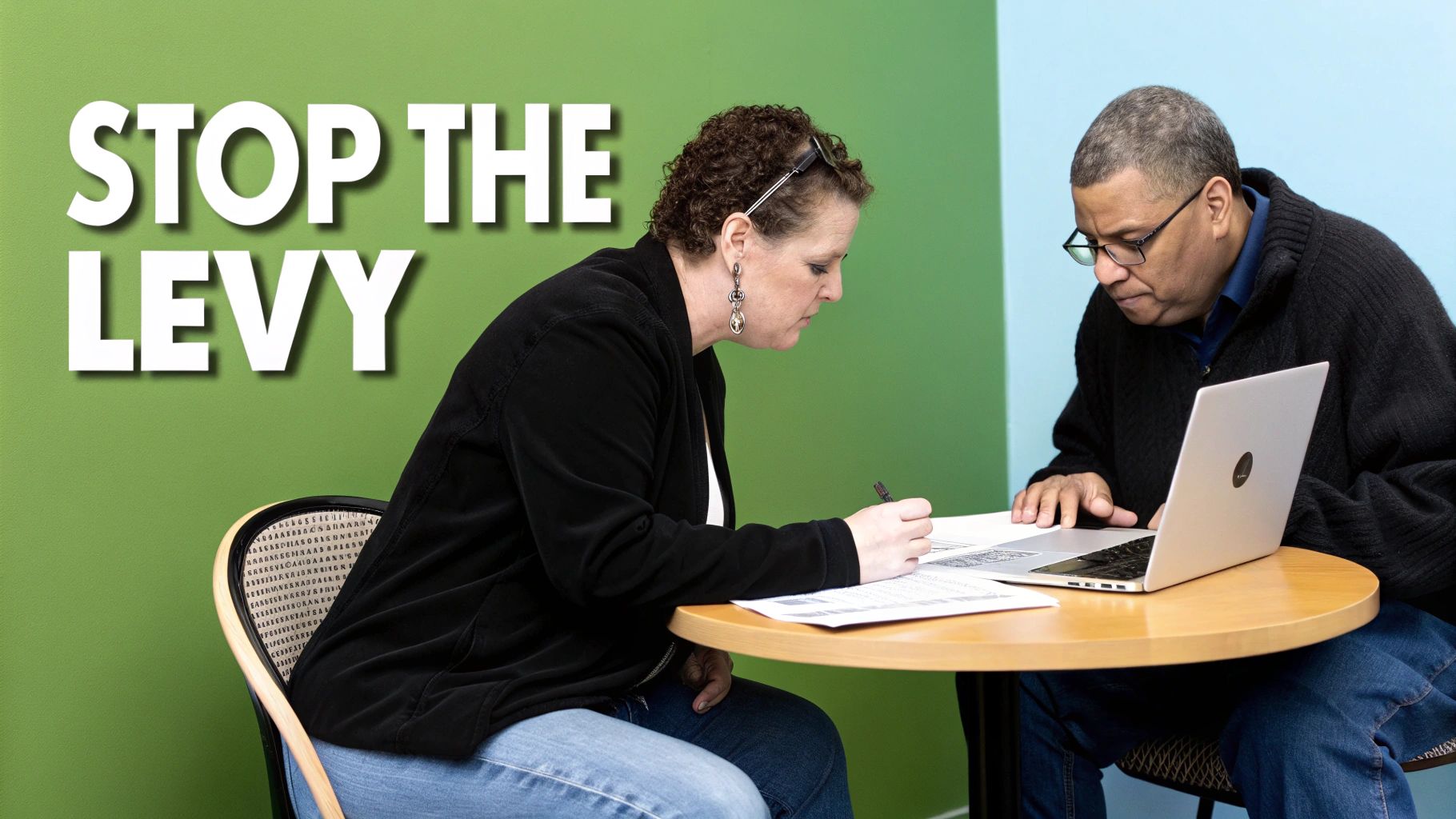 A person signing a document at a desk, symbolizing taking action to resolve tax debt.