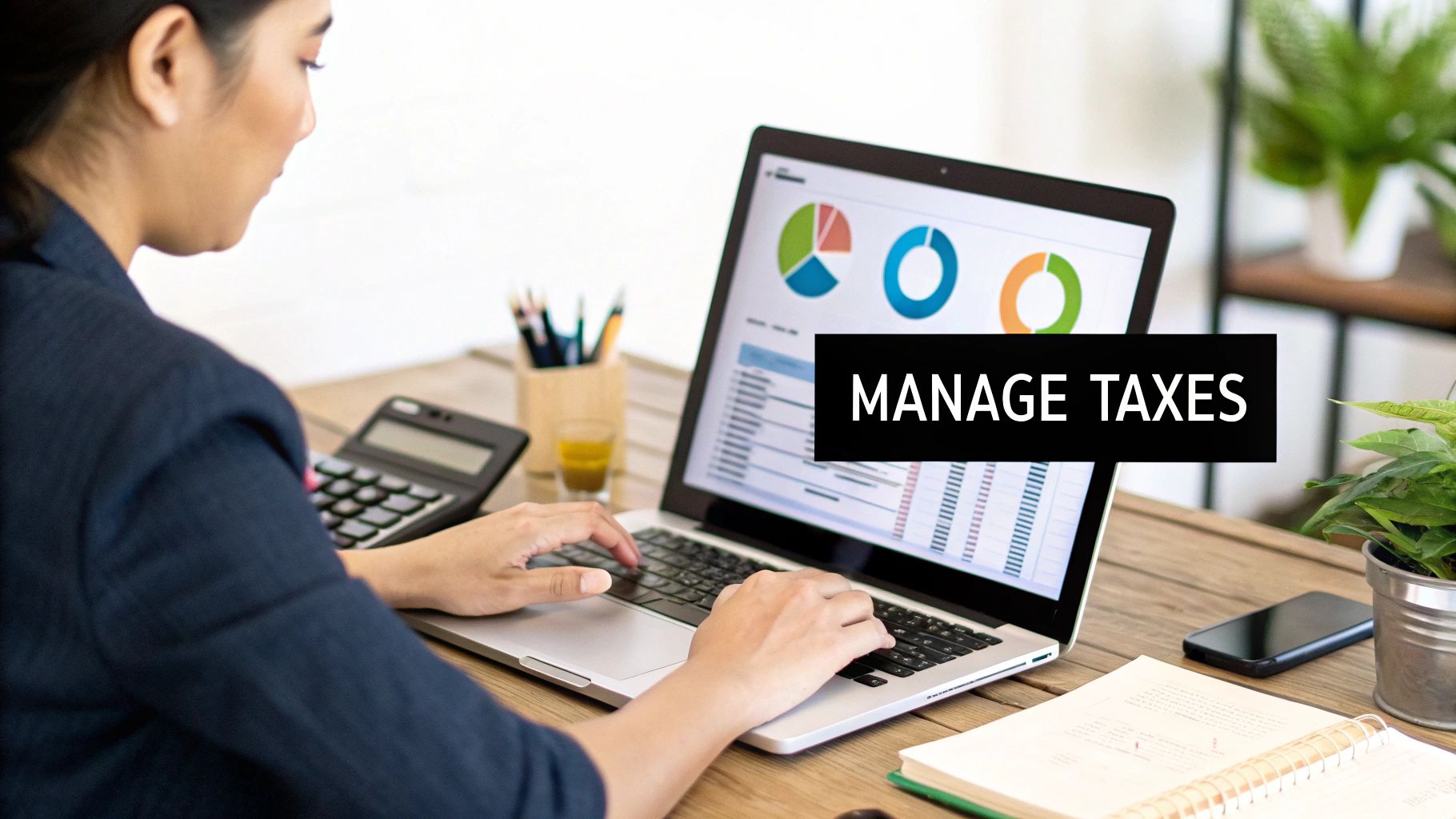 A person managing taxes on a laptop, with financial charts on the screen and a calculator.